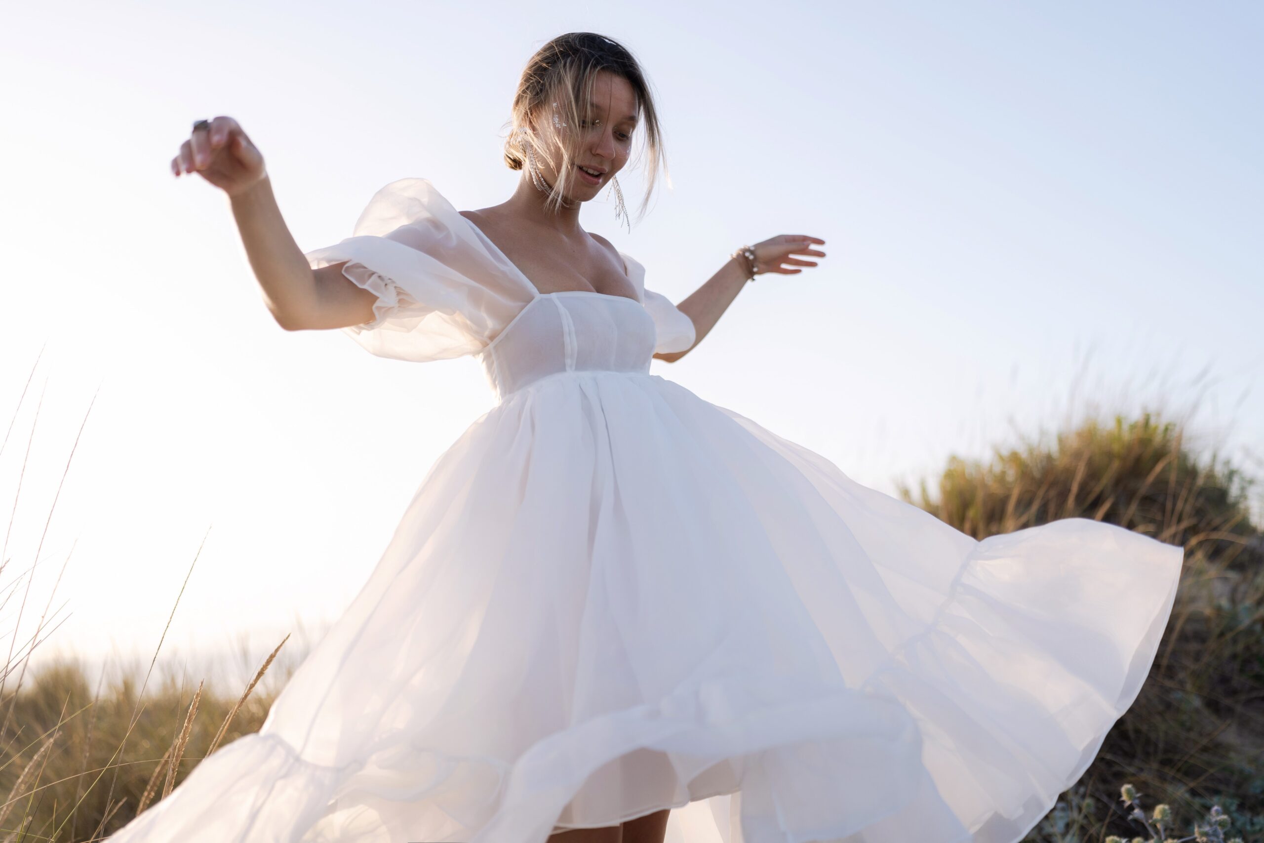 Bride twirling among the dune grass at Costa da Caparica, with the low sun behind her lighting the skirt Bride twirling among the dune grass at Costa da Caparica, with the low sun behind her lighting the skirt