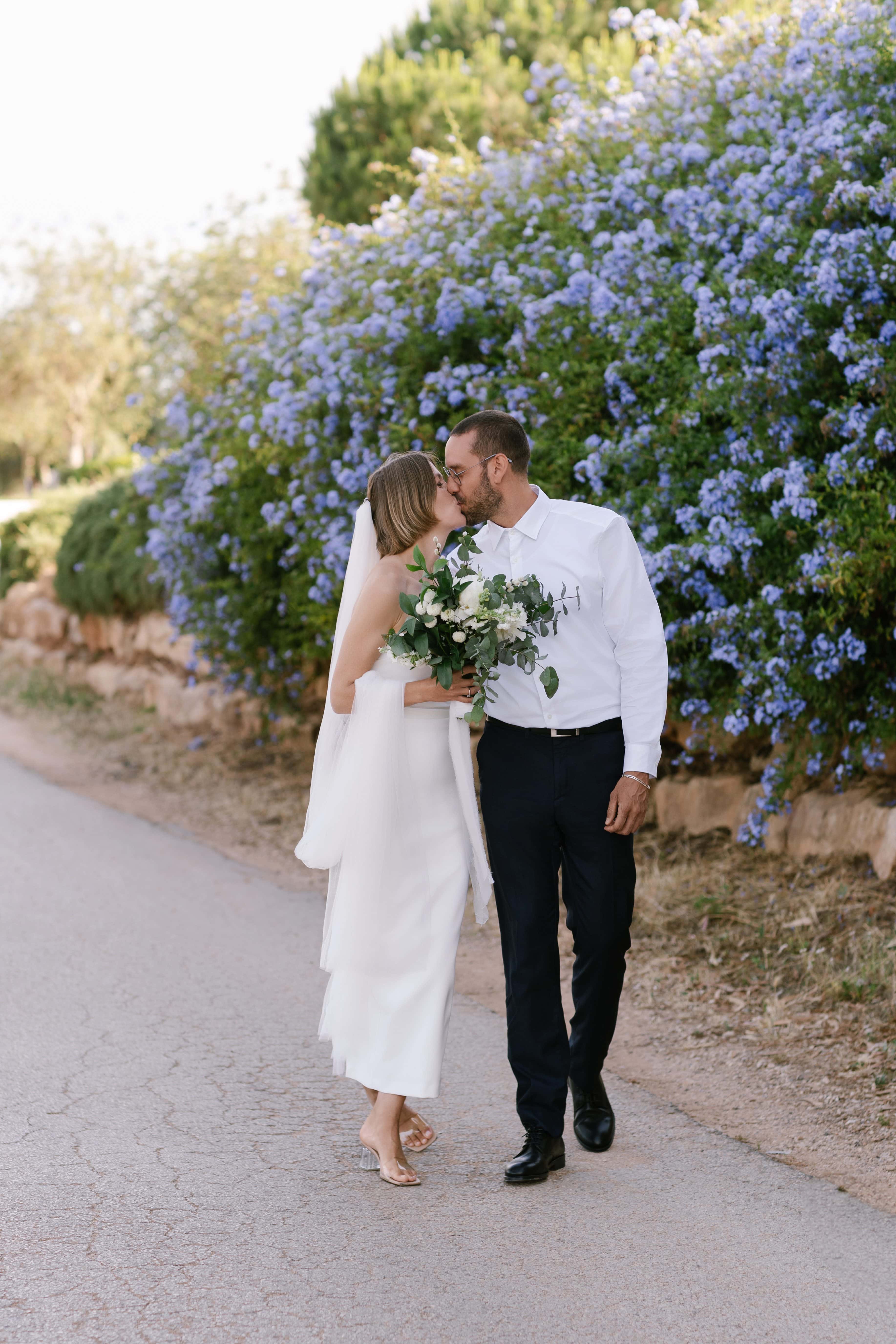 Bride and groom walking along a lane lined with blue flowers, Algarve elopement Bride and groom walking along a lane lined with blue flowers, Algarve elopement