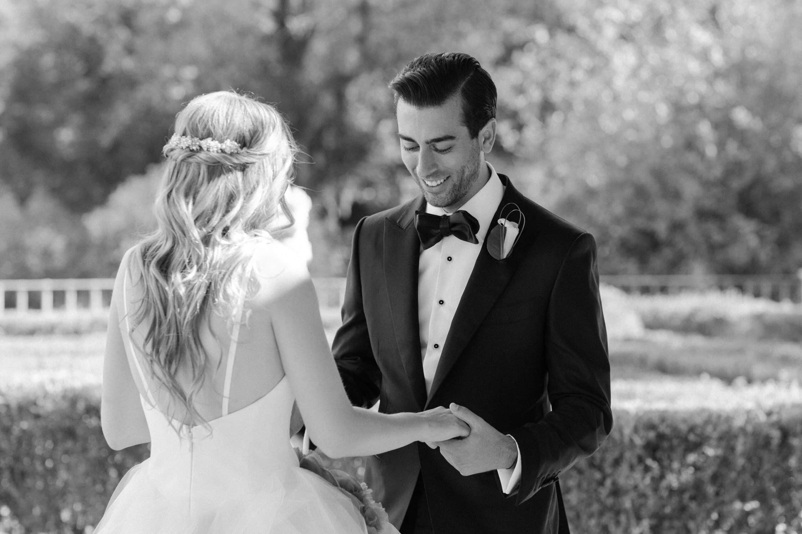 Groom smiling at his bride during a poignant First Look in monochrome elegance. Groom smiling at his bride during a poignant First Look in monochrome elegance.