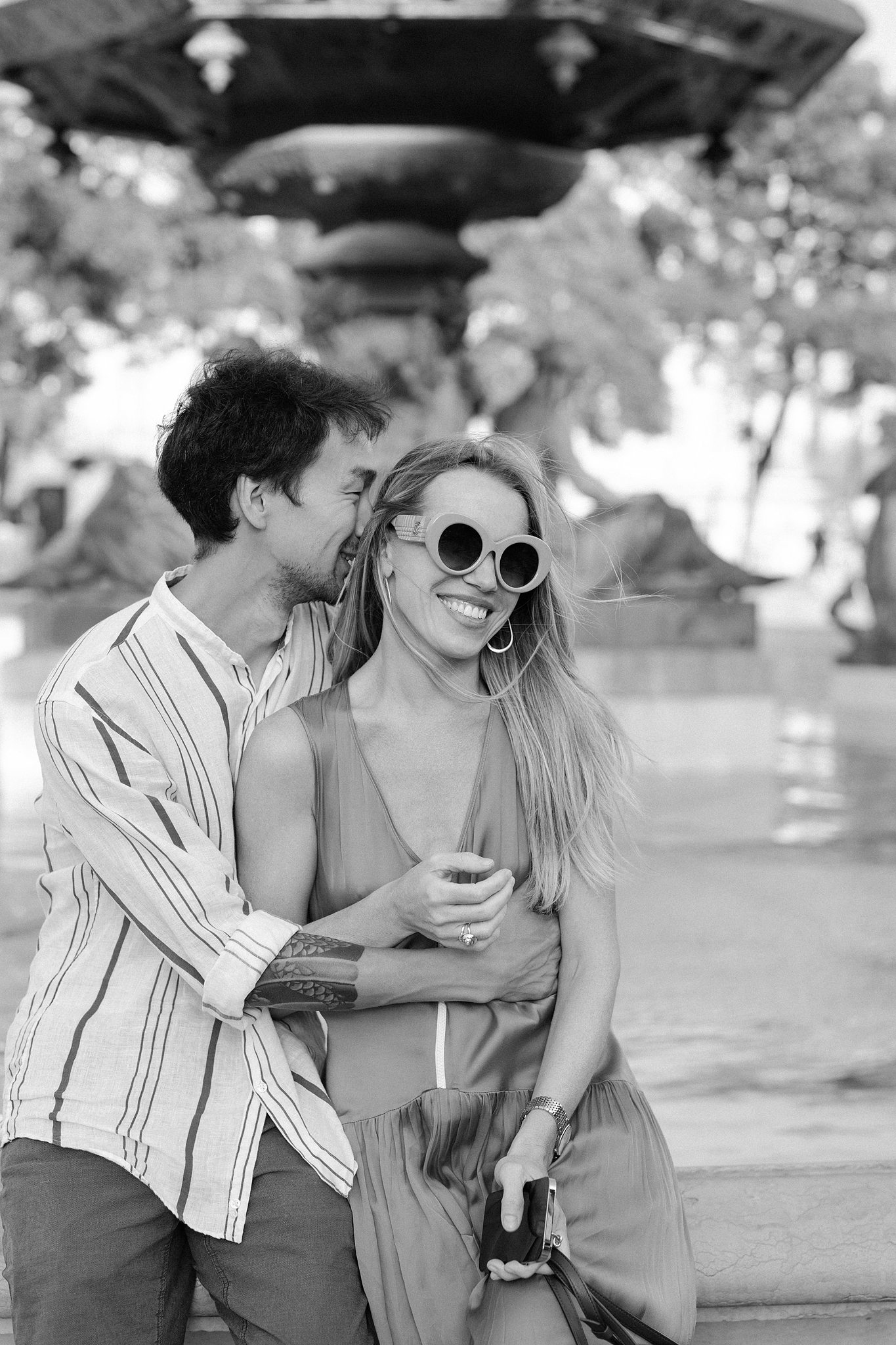 Couple laughing and hugging by a fountain in central Lisbon, black and white Couple laughing and hugging by a fountain in central Lisbon, black and white