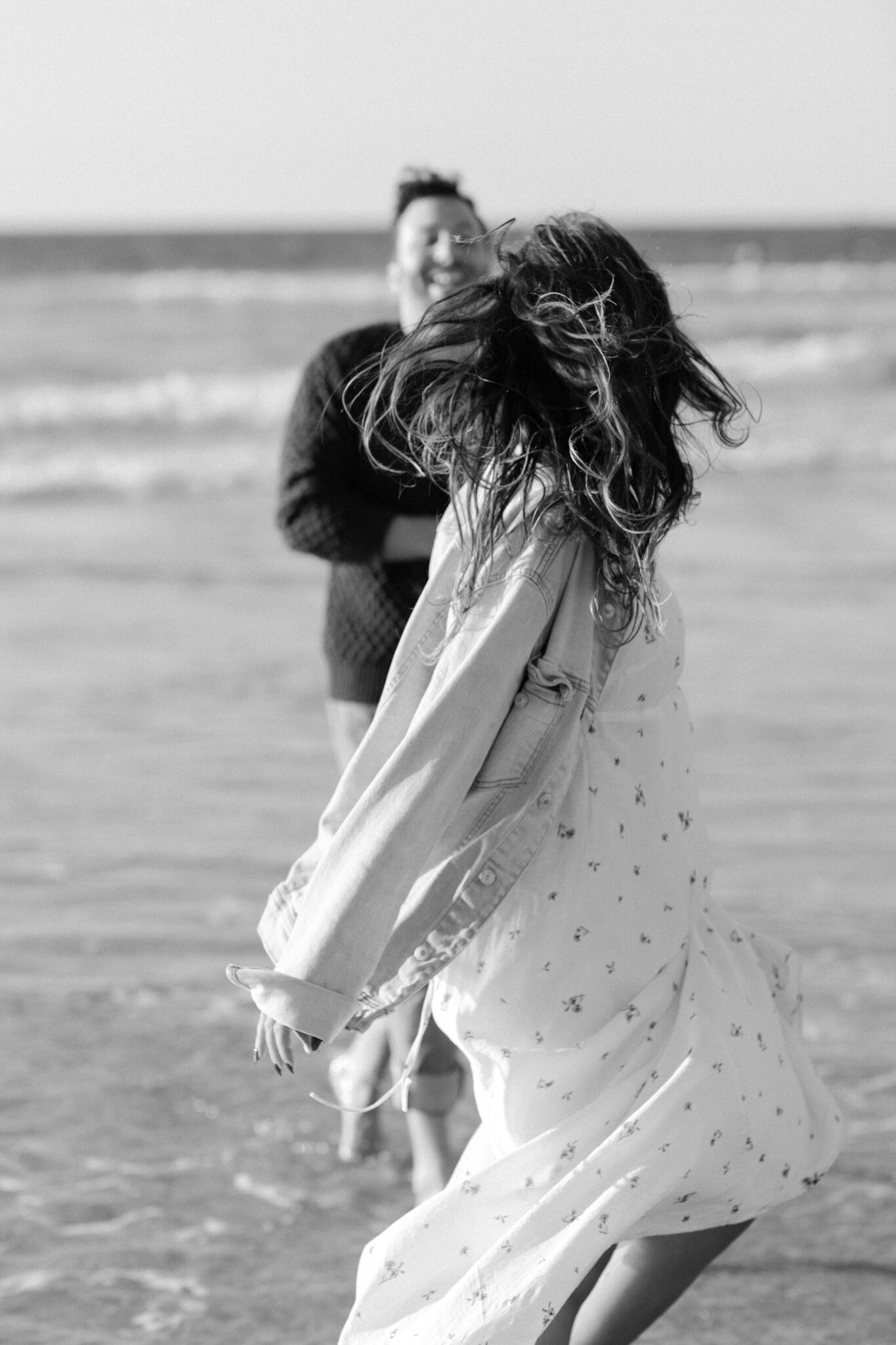 Woman spinning in shallow water at Guincho, her hair and dress blown by the wind, Cascais, black and white Woman spinning in shallow water at Guincho, her hair and dress blown by the wind, Cascais, black and white