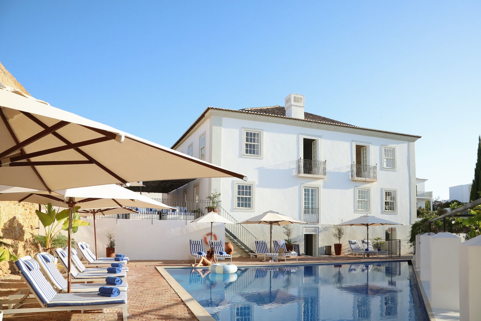 The white main house and the pool with parasols, Casa Mãe, Lagos The white main house and the pool with parasols, Casa Mãe, Lagos
