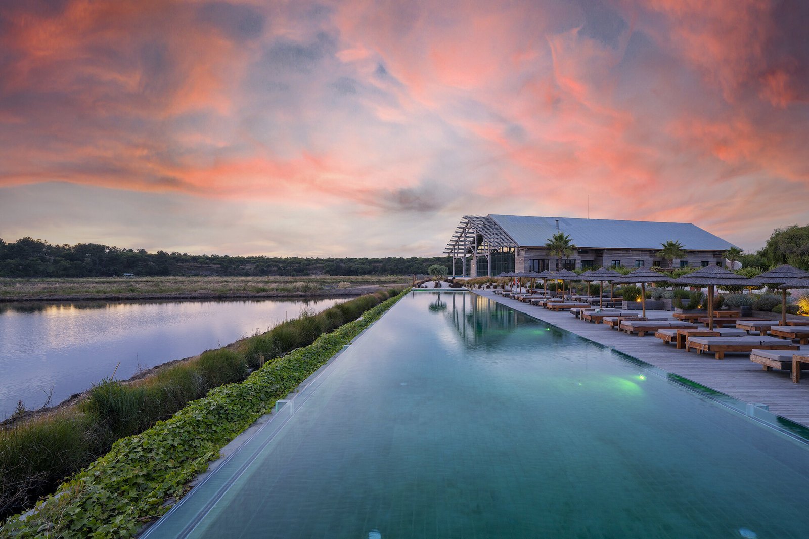 Infinity pool facing the rice fields under a pink sunset sky, Quinta da Comporta Infinity pool facing the rice fields under a pink sunset sky, Quinta da Comporta
