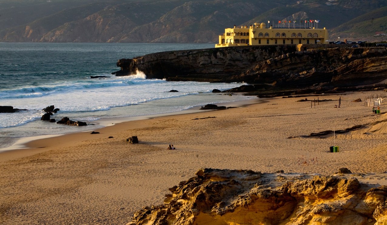 The yellow Fortaleza do Guincho on its rocky headland across the sand and surf of the beach, Cascais The yellow Fortaleza do Guincho on its rocky headland across the sand and surf of the beach, Cascais