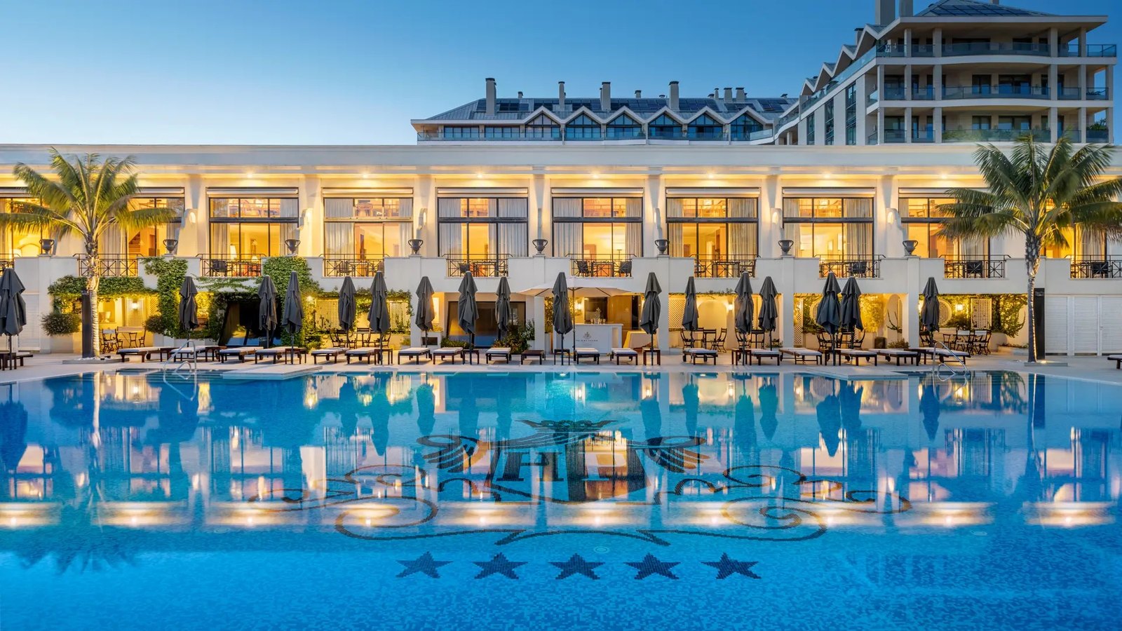 The colonnaded facade and the pool of the Palácio Estoril lit up in the evening The colonnaded facade and the pool of the Palácio Estoril lit up in the evening