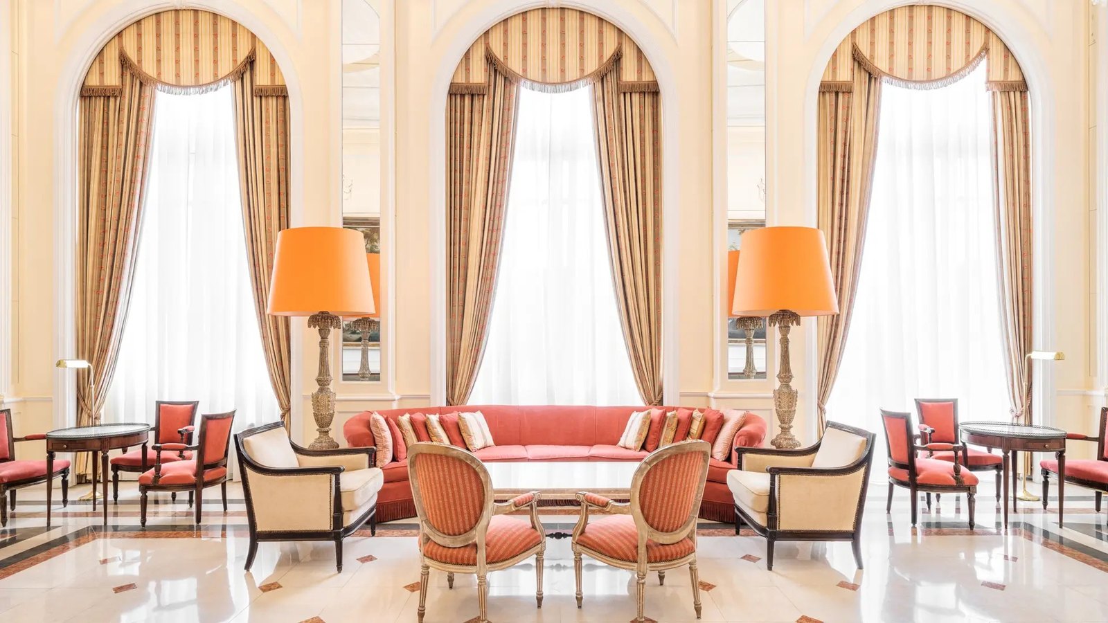 Salon with arched windows, striped curtains and coral armchairs at the Palácio Estoril Salon with arched windows, striped curtains and coral armchairs at the Palácio Estoril