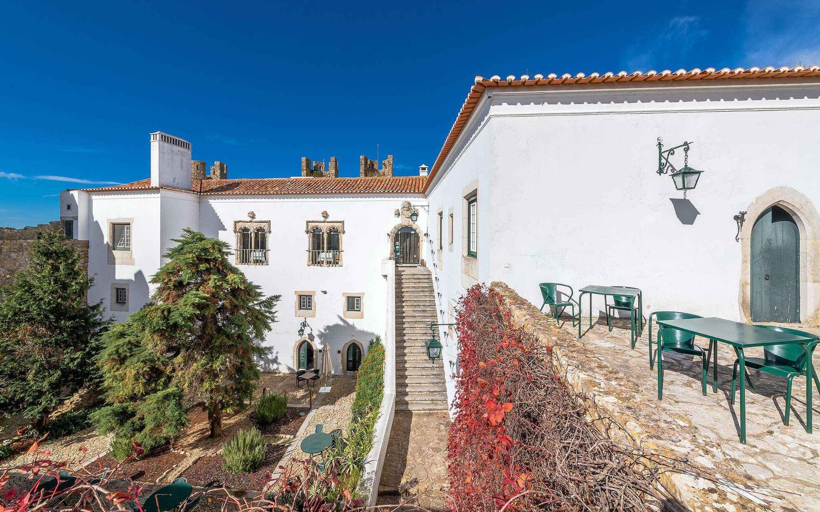 The whitewashed castle with its stone stairs, a garden terrace and red autumn vines, Pousada Castelo de Óbidos The whitewashed castle with its stone stairs, a garden terrace and red autumn vines, Pousada Castelo de Óbidos