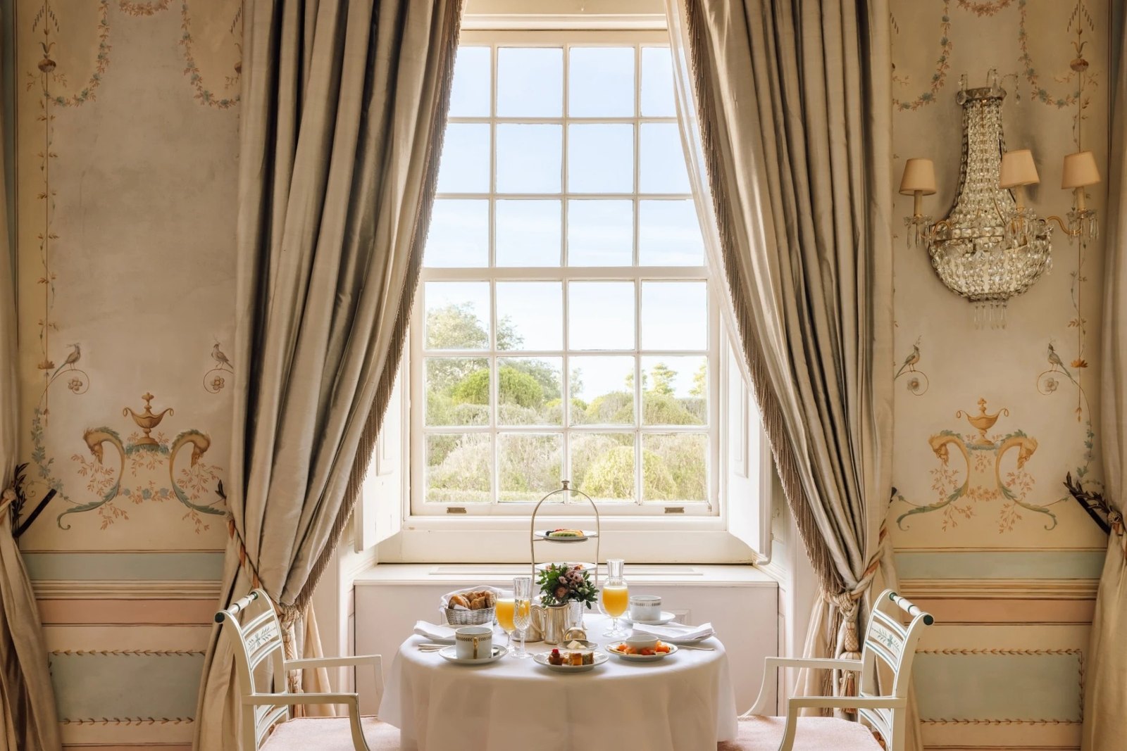 Breakfast table for two at a tall window with painted walls and long curtains, Palácio de Seteais, Sintra Breakfast table for two at a tall window with painted walls and long curtains, Palácio de Seteais, Sintra
