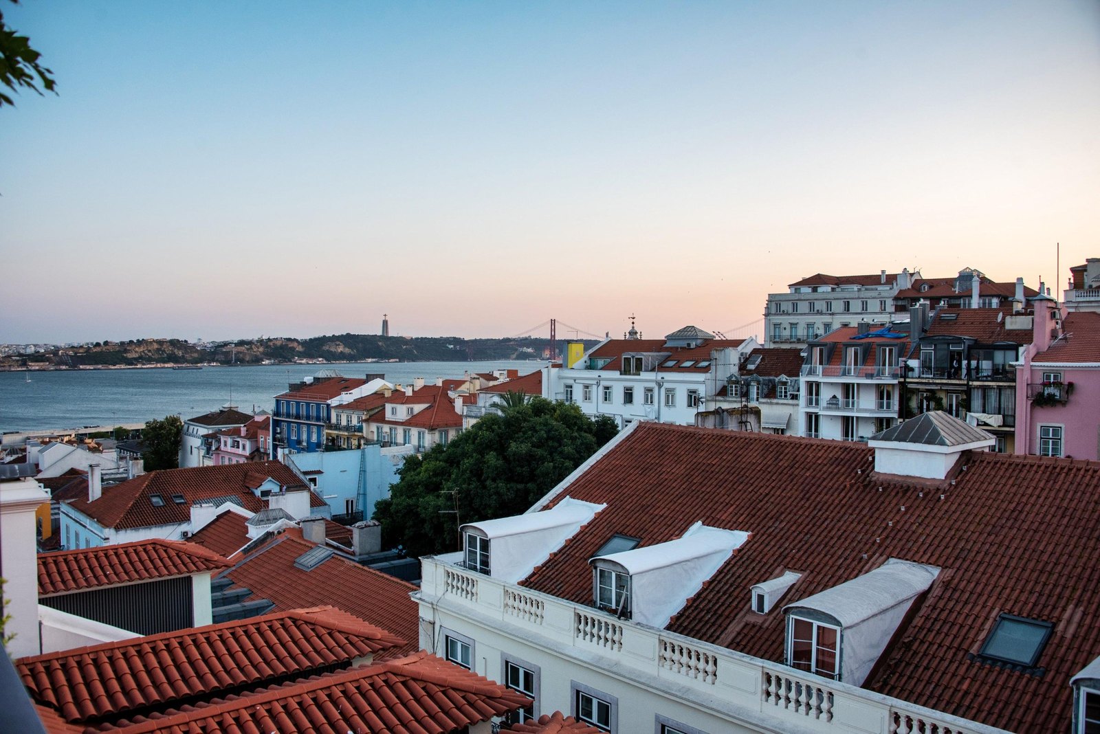 Blue hour over Lisbon's red rooftops, the river and the 25 de Abril Bridge from the Bairro Alto Hotel Blue hour over Lisbon's red rooftops, the river and the 25 de Abril Bridge from the Bairro Alto Hotel