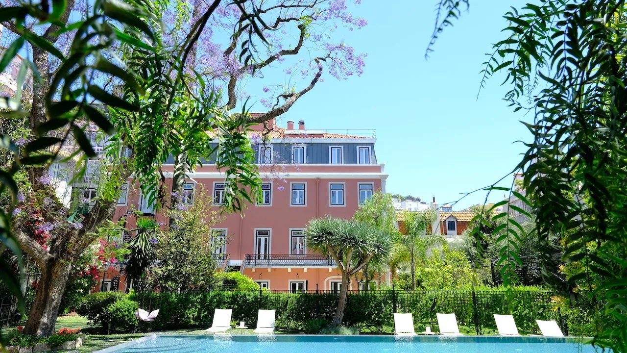 The pink palace seen across a pool through palms and a flowering jacaranda, Palácio Príncipe Real, Lisbon The pink palace seen across a pool through palms and a flowering jacaranda, Palácio Príncipe Real, Lisbon