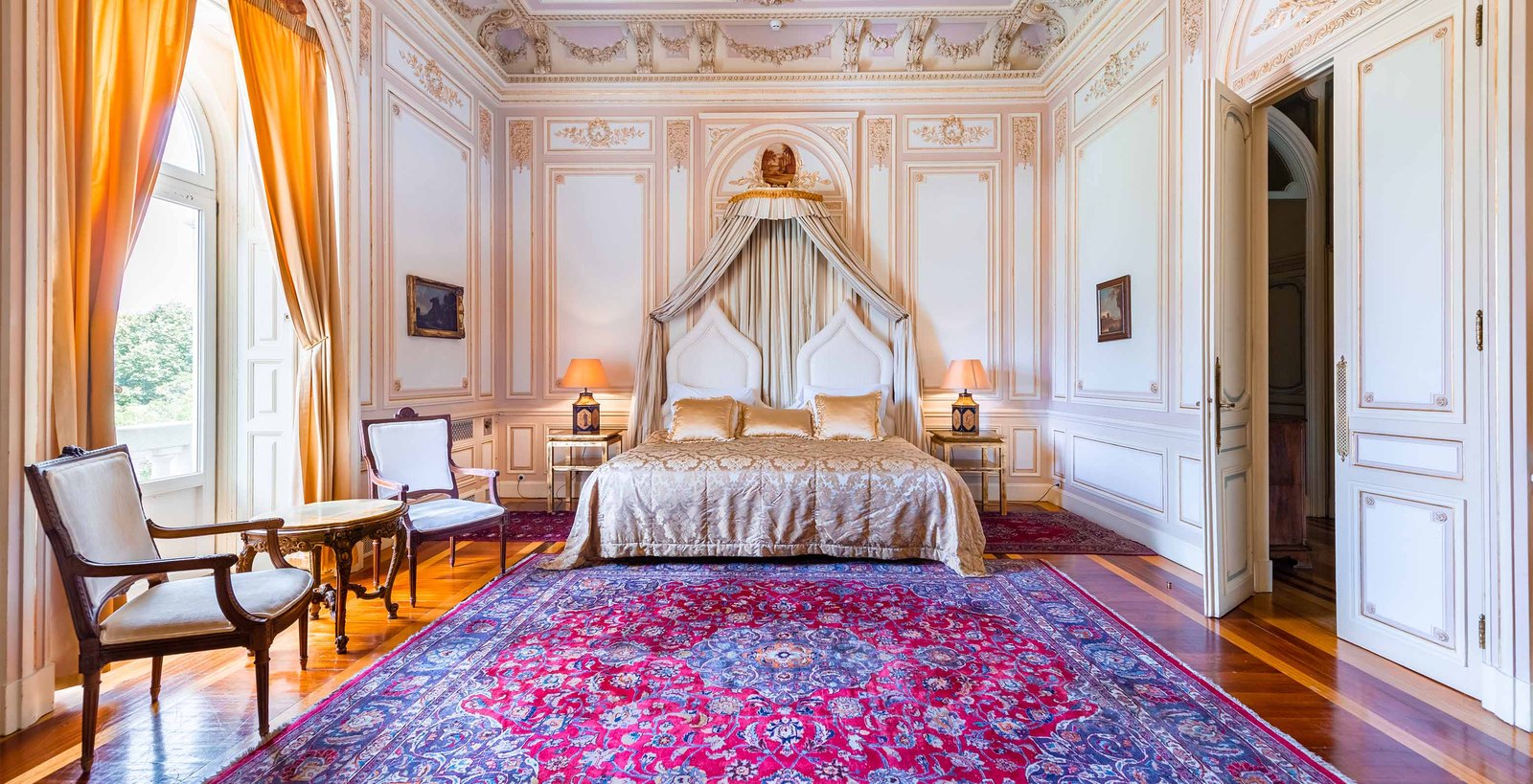 The Dom Carlos Royal Suite with a canopy bed, painted ceilings and a red rug, Pestana Palace, Lisbon The Dom Carlos Royal Suite with a canopy bed, painted ceilings and a red rug, Pestana Palace, Lisbon