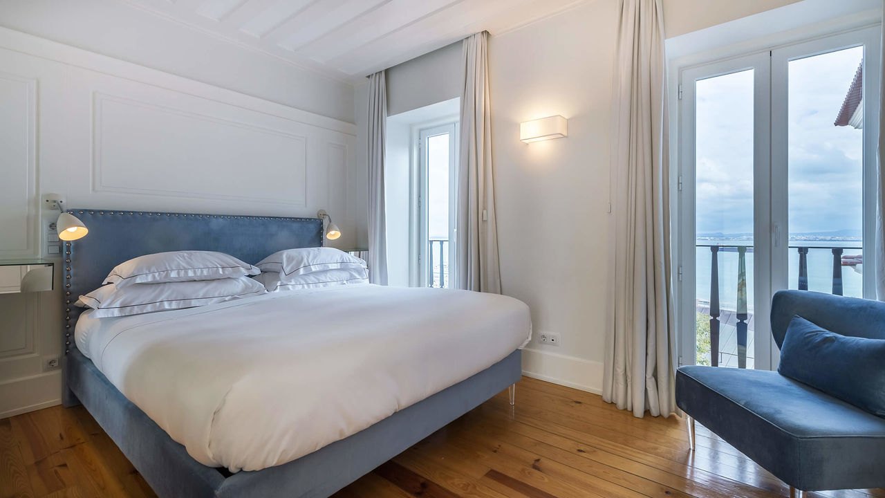 Bright bedroom with a balcony door open onto the river view, Santiago de Alfama, Lisbon Bright bedroom with a balcony door open onto the river view, Santiago de Alfama, Lisbon
