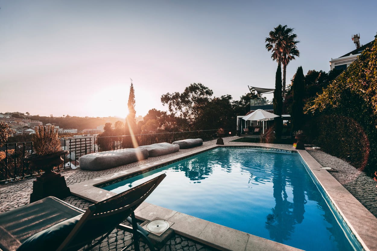 Pool on the hilltop terrace at sunset with palm trees and the city behind, Torel Palace, Lisbon Pool on the hilltop terrace at sunset with palm trees and the city behind, Torel Palace, Lisbon