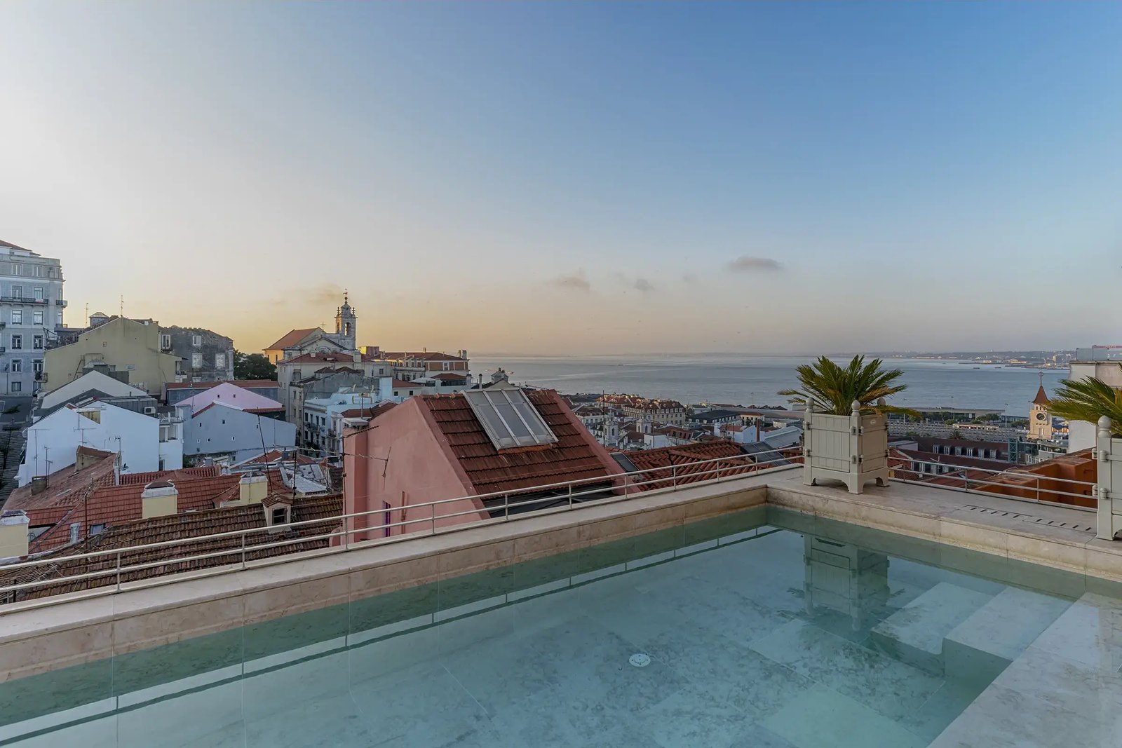 Rooftop pool looking over the old town's roofs to the river at dusk, Verride Palácio Santa Catarina, Lisbon Rooftop pool looking over the old town's roofs to the river at dusk, Verride Palácio Santa Catarina, Lisbon