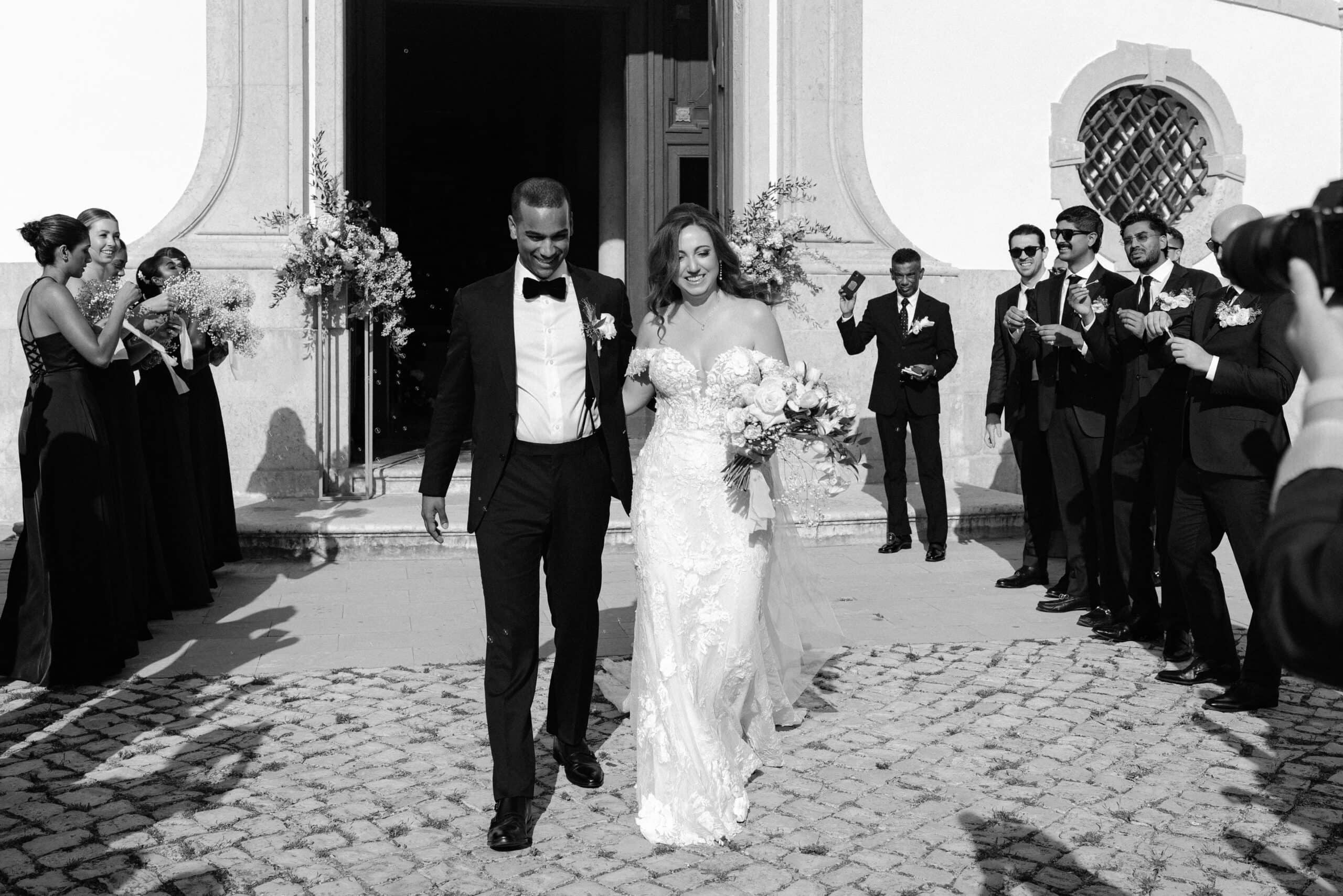 Bridesmaids and groomsmen applauding as a bride and groom leave a church in Óbidos, Portugal Bridesmaids and groomsmen applauding as a bride and groom leave a church in Óbidos, Portugal