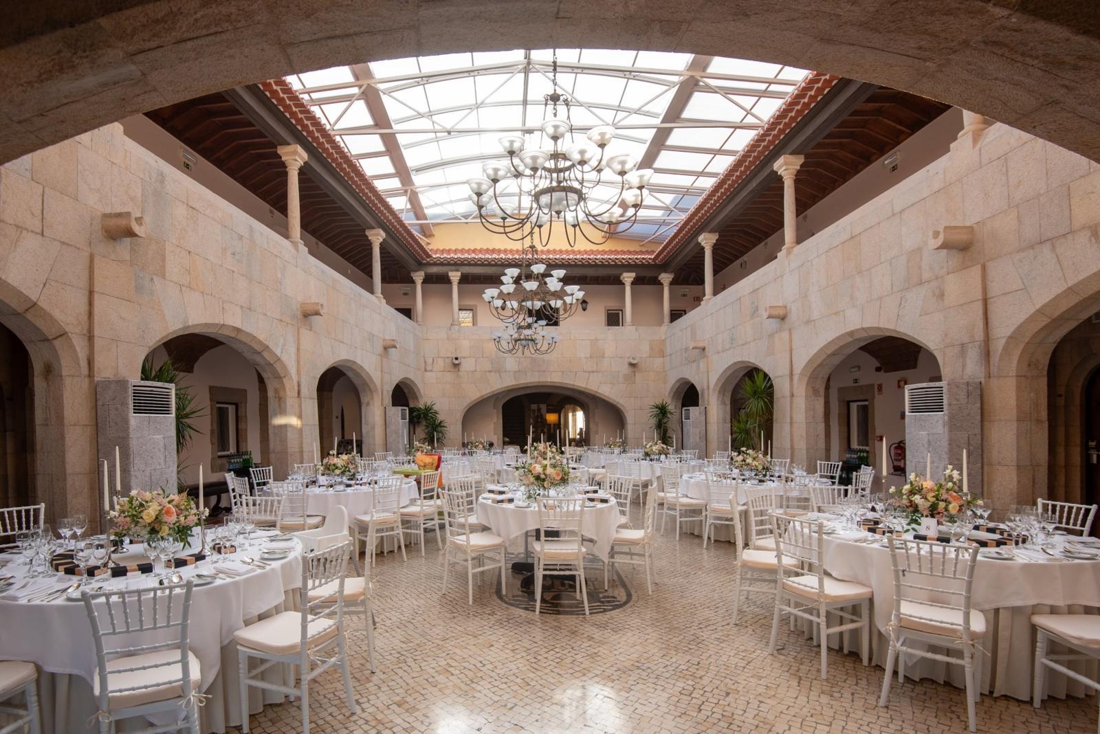 Skylit stone hall with chandeliers set for a banquet at Fortaleza do Guincho, Cascais