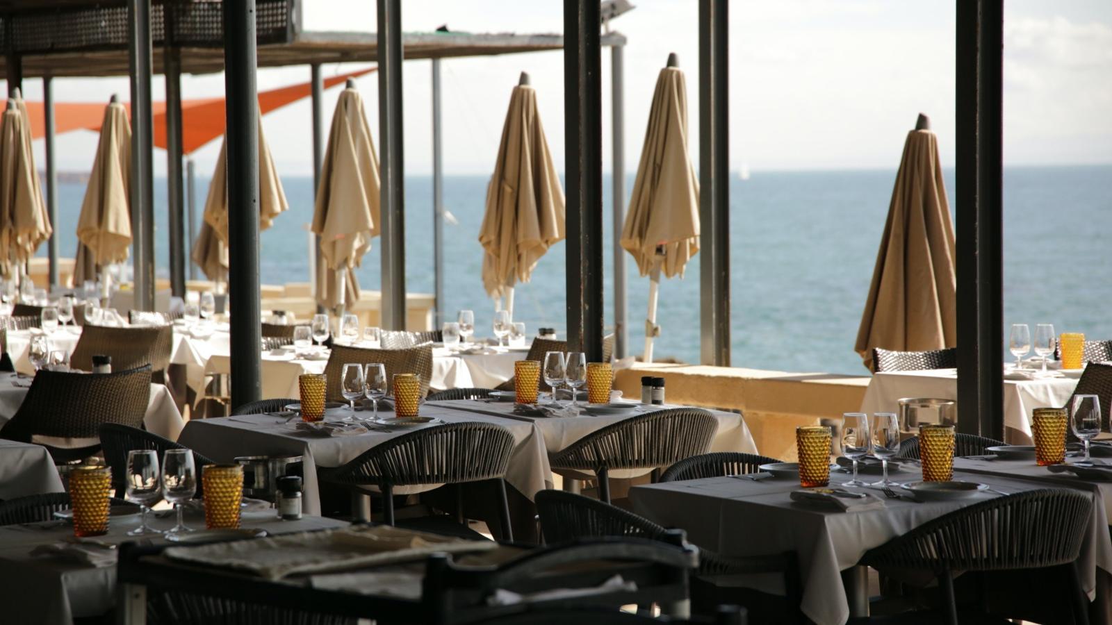 Terrace tables under parasols above the rocks and the open Atlantic, Furnas do Guincho, Cascais