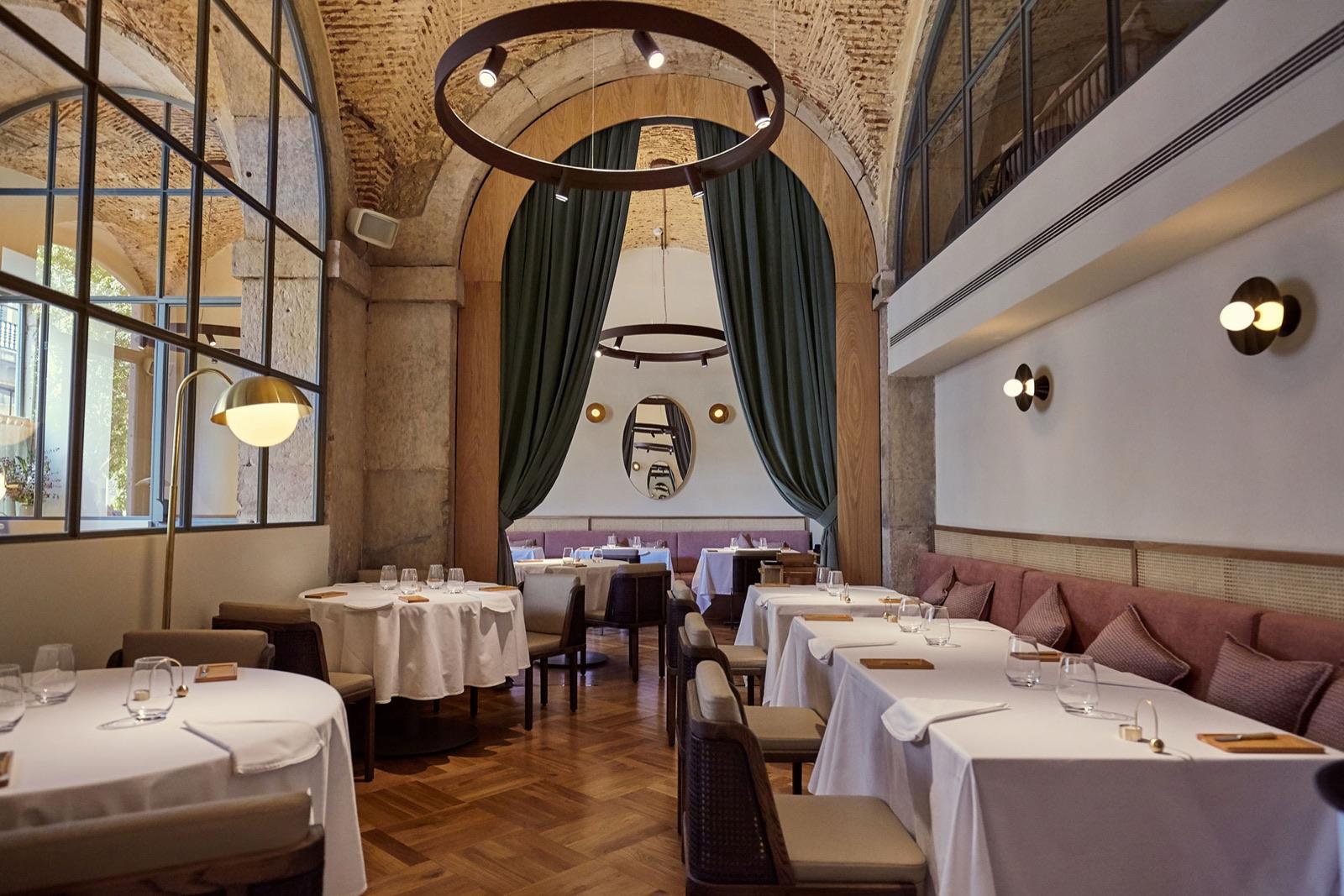 Belcanto's dining room in Chiado with vaulted stone ceilings, tall arched windows and white-clothed tables, Lisbon
