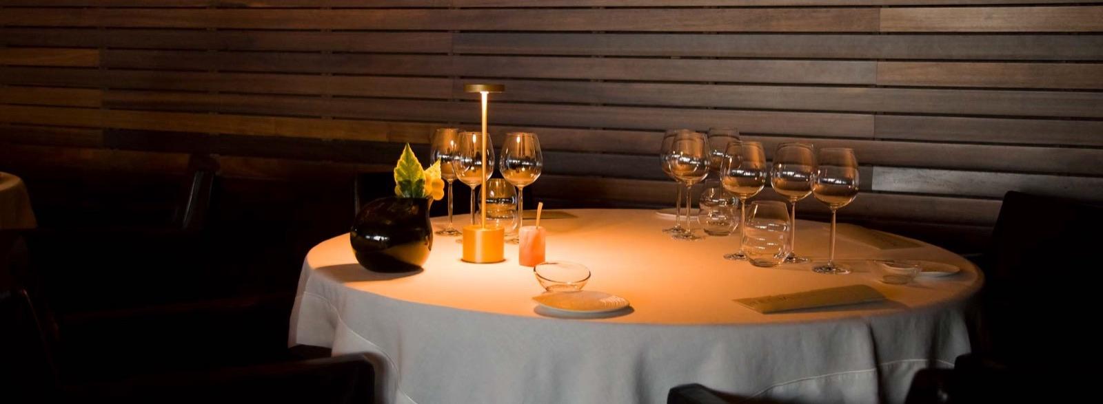 Candlelit round table set with glasses against a dark wooden wall at Feitoria, Belém, Lisbon