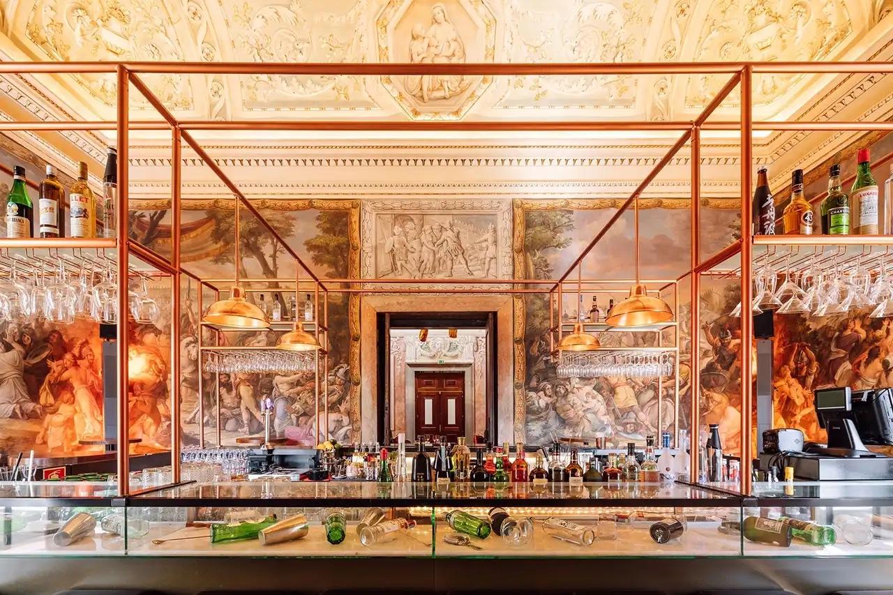 Bar framed in copper beneath painted frescoes at Palácio Chiado, Lisbon