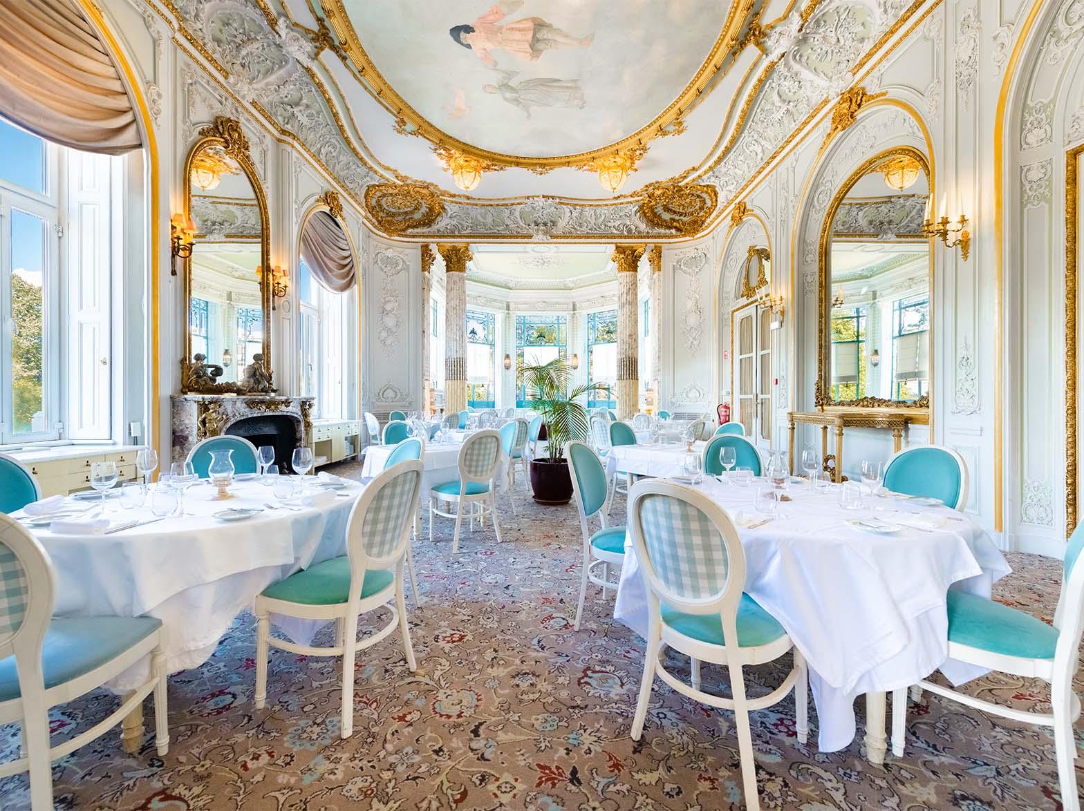 Former ballroom with a painted ceiling, white tables and turquoise chairs at Valle Flôr, Pestana Palace, Lisbon