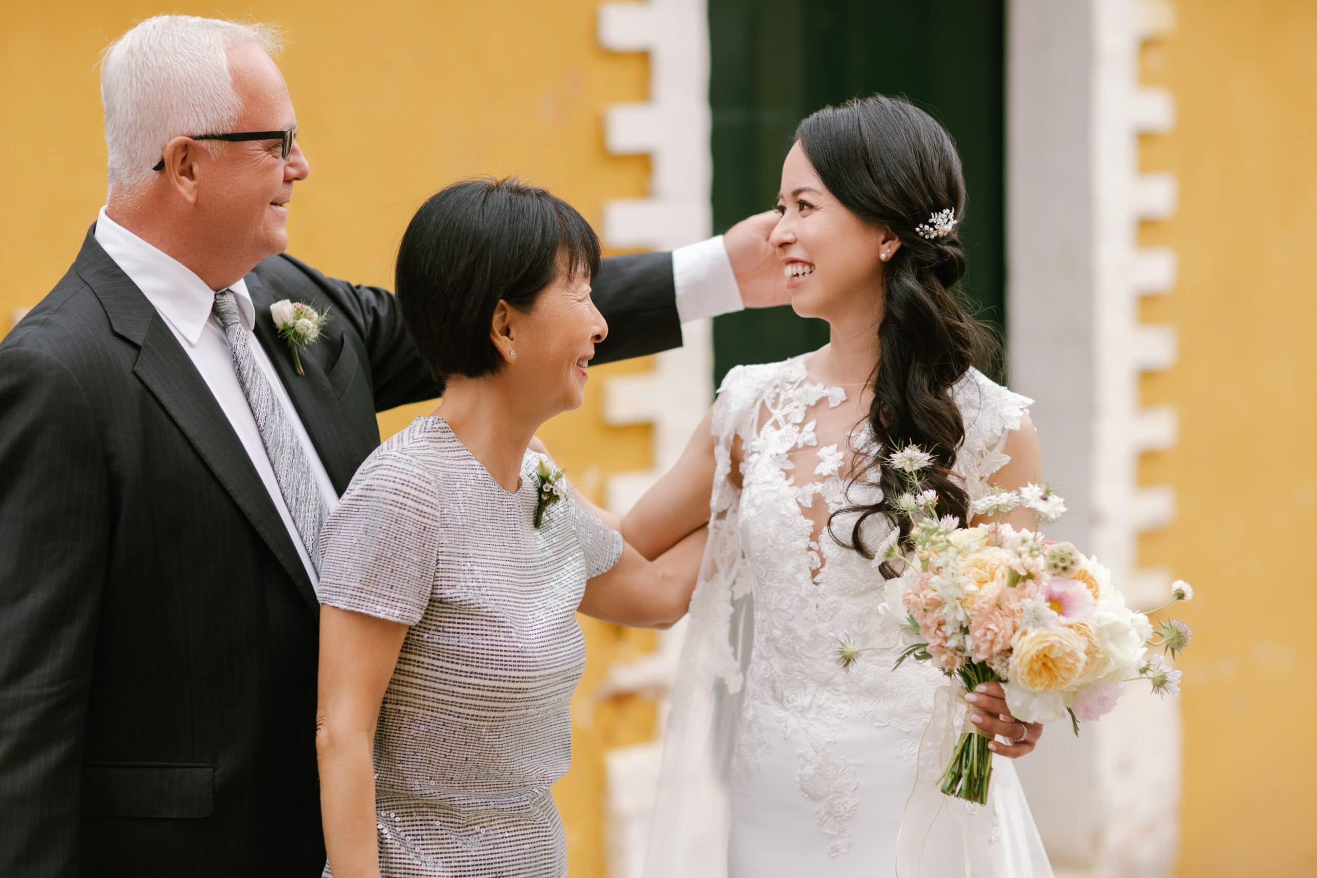 Bride laughing with her parents during a heartwarming First Look on her wedding day.