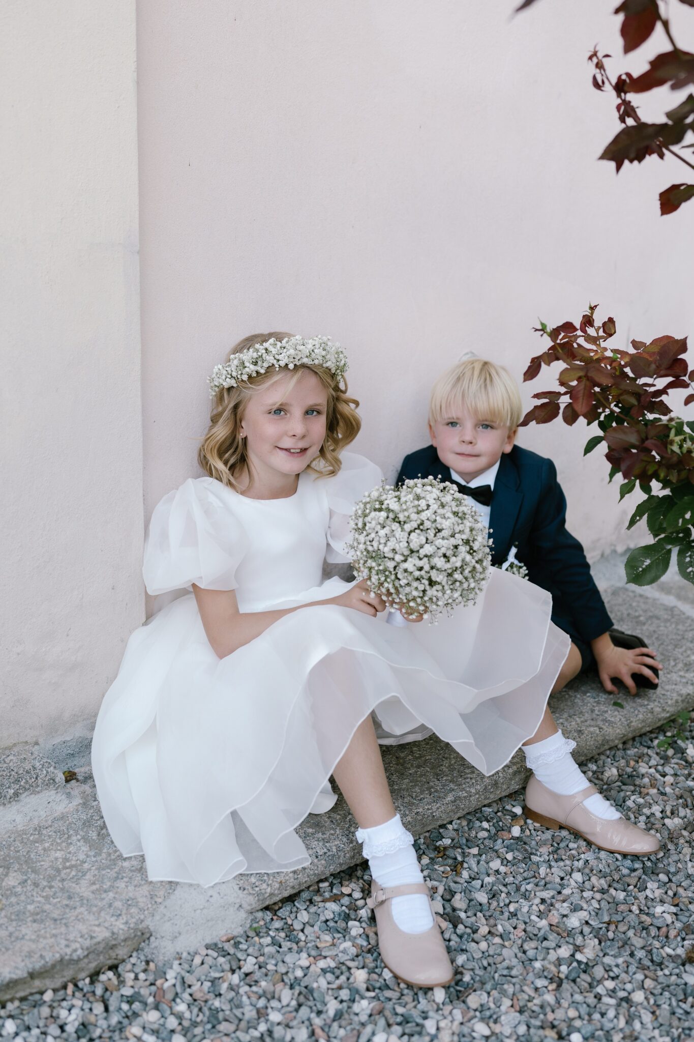 Flower girl with a flower crown and young ring bearer sitting together during a Lake Como wedding at Villa Carlotta