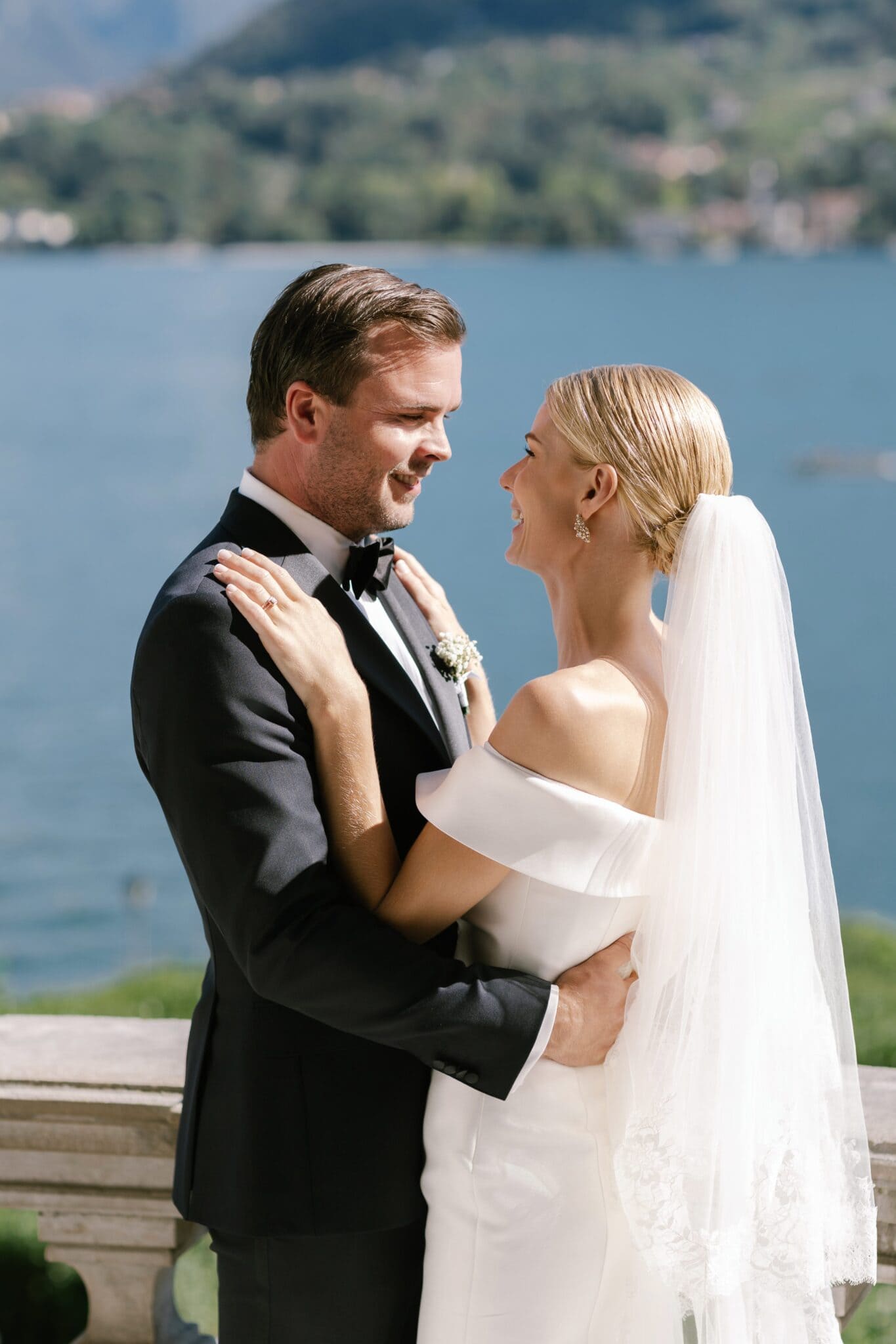 Bride and groom holding each other with Lake Como in the background.