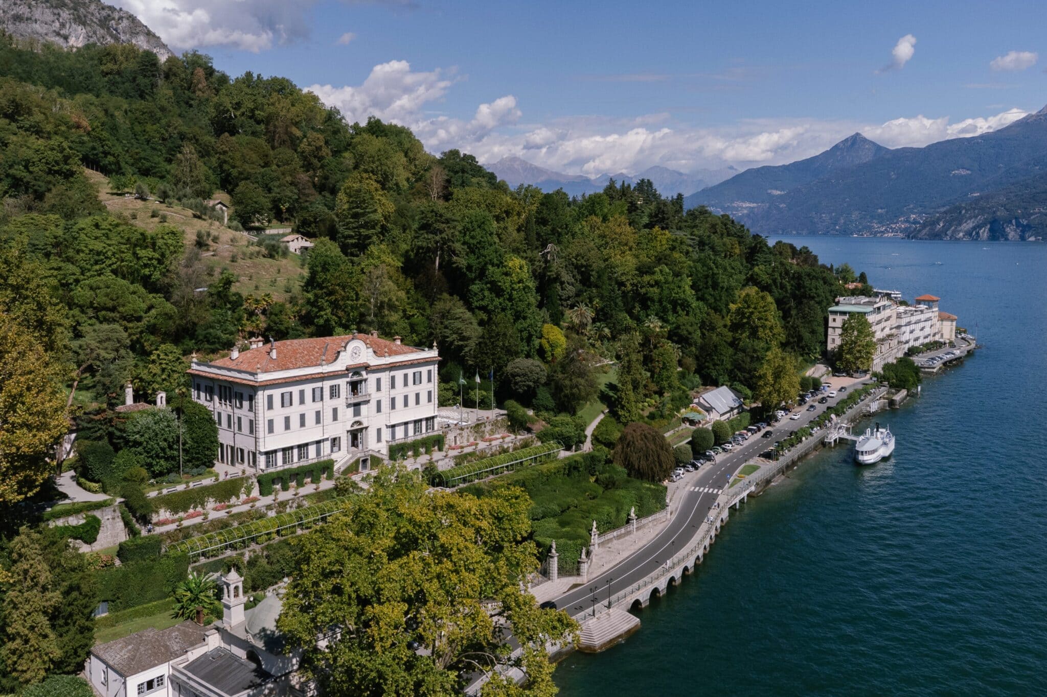 Aerial view of Villa Carlotta surrounded by lush gardens and overlooking the blue waters of Lake Como, Italy