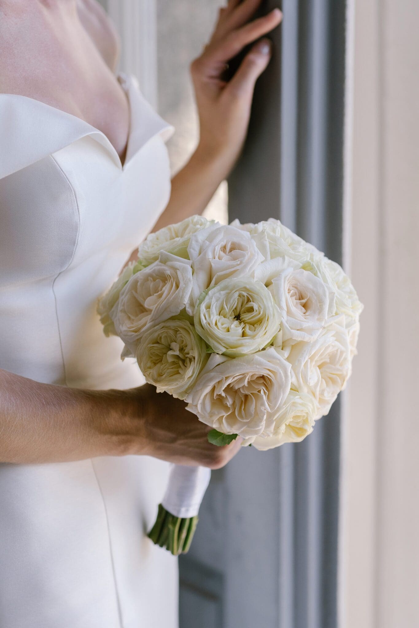Close-up of the bride’s bouquet of ivory roses, held near a window at Villa Carlotta, Lake Como.