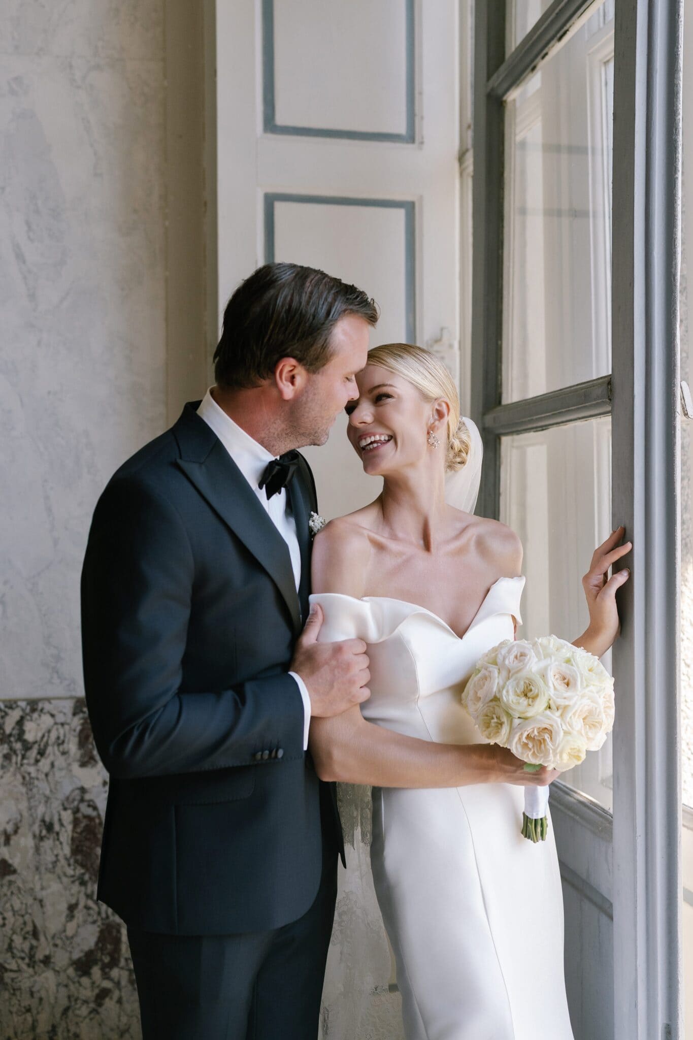 Bride and groom sharing a tender moment by the window inside Villa Carlotta, Lake Como.
