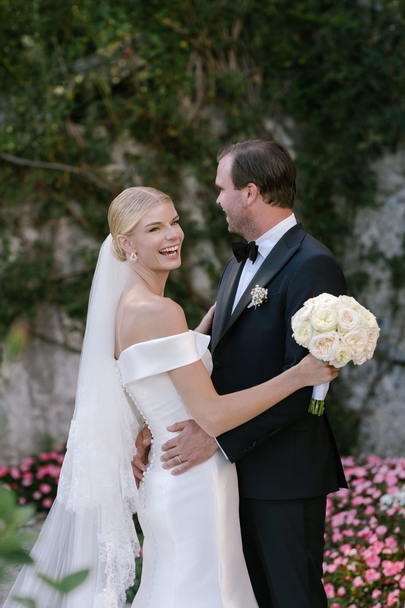 Bride laughing joyfully with bouquet in hand as groom stands beside her at Villa Carlotta.