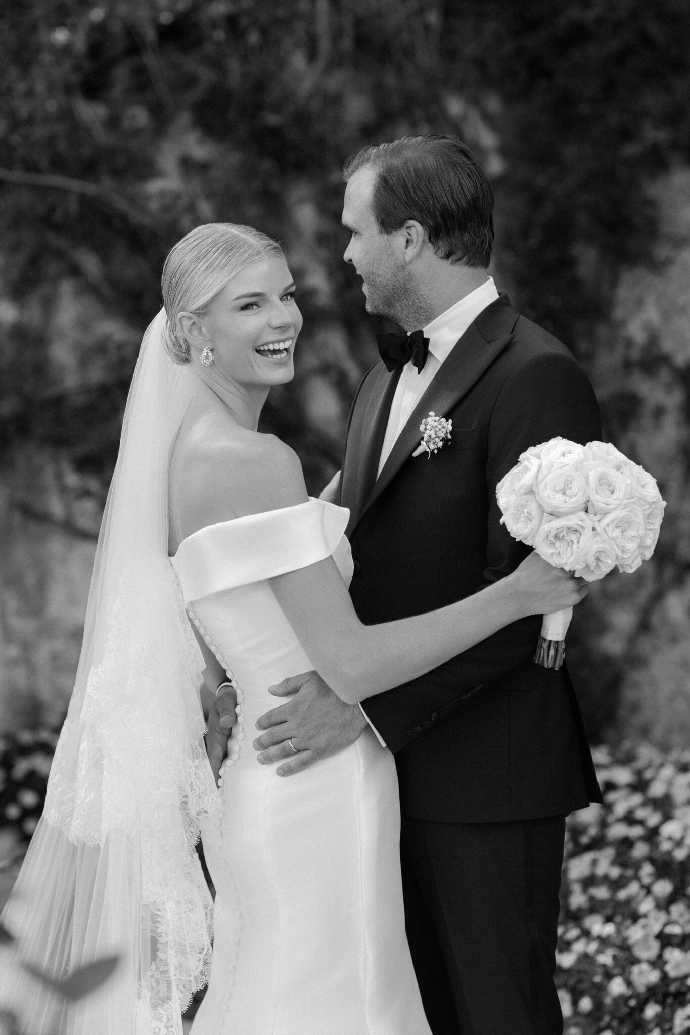 Bride laughing joyfully while holding her bouquet, embraced by the groom during their wedding at Villa Carlotta, Lake Como