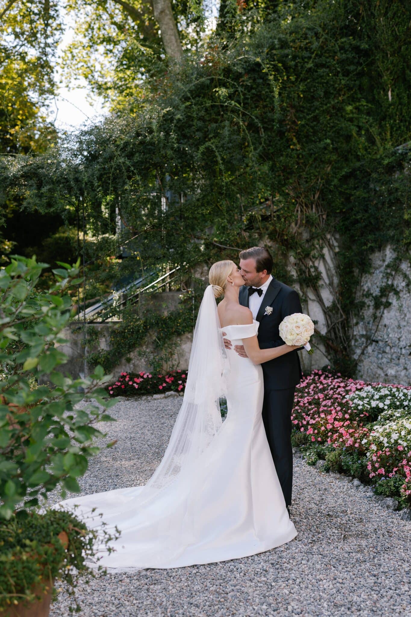 Bride and groom sharing a kiss in the lush gardens of Villa Carlotta, Lake Como.