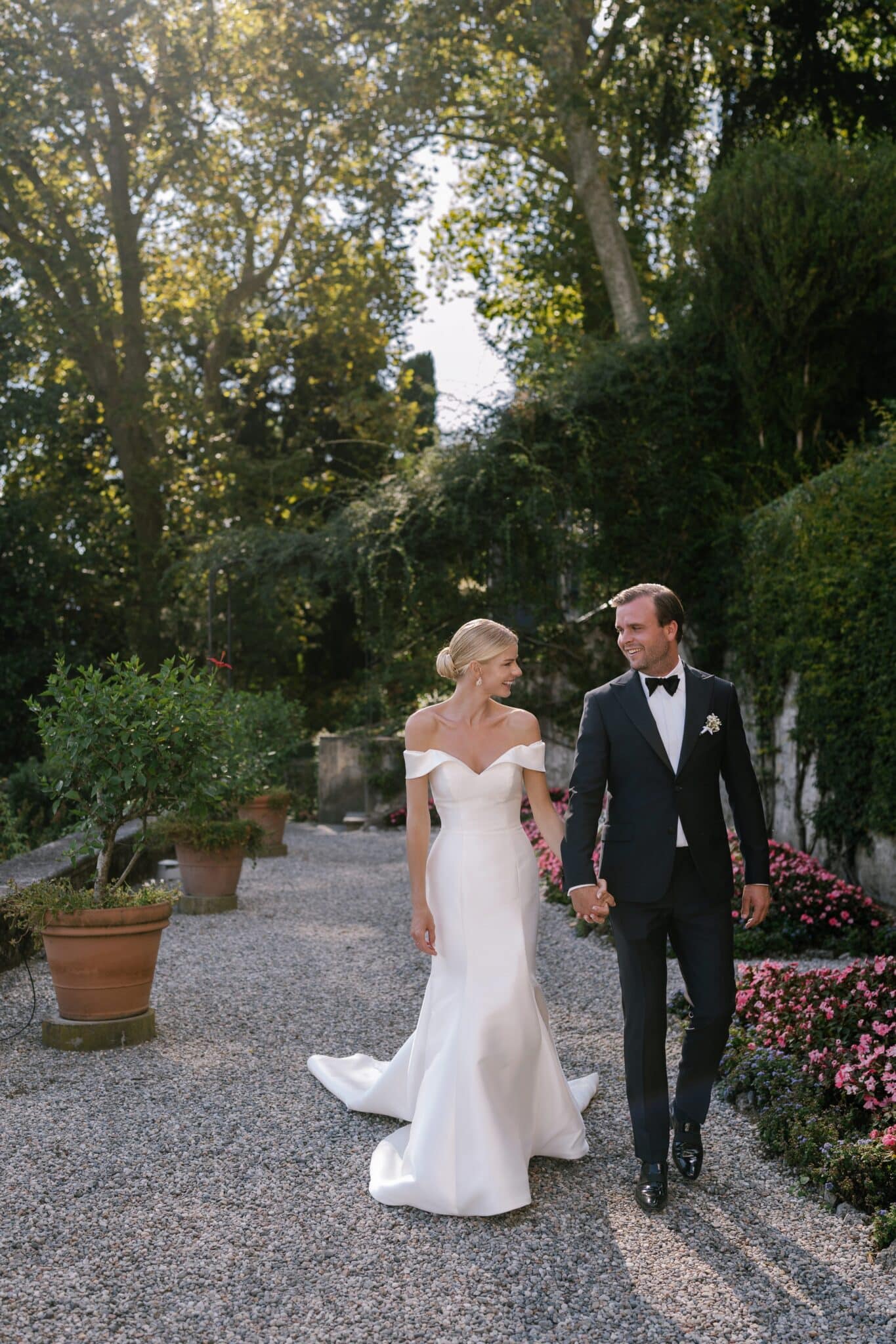Bride and groom walking hand in hand through the gardens of Villa Carlotta.