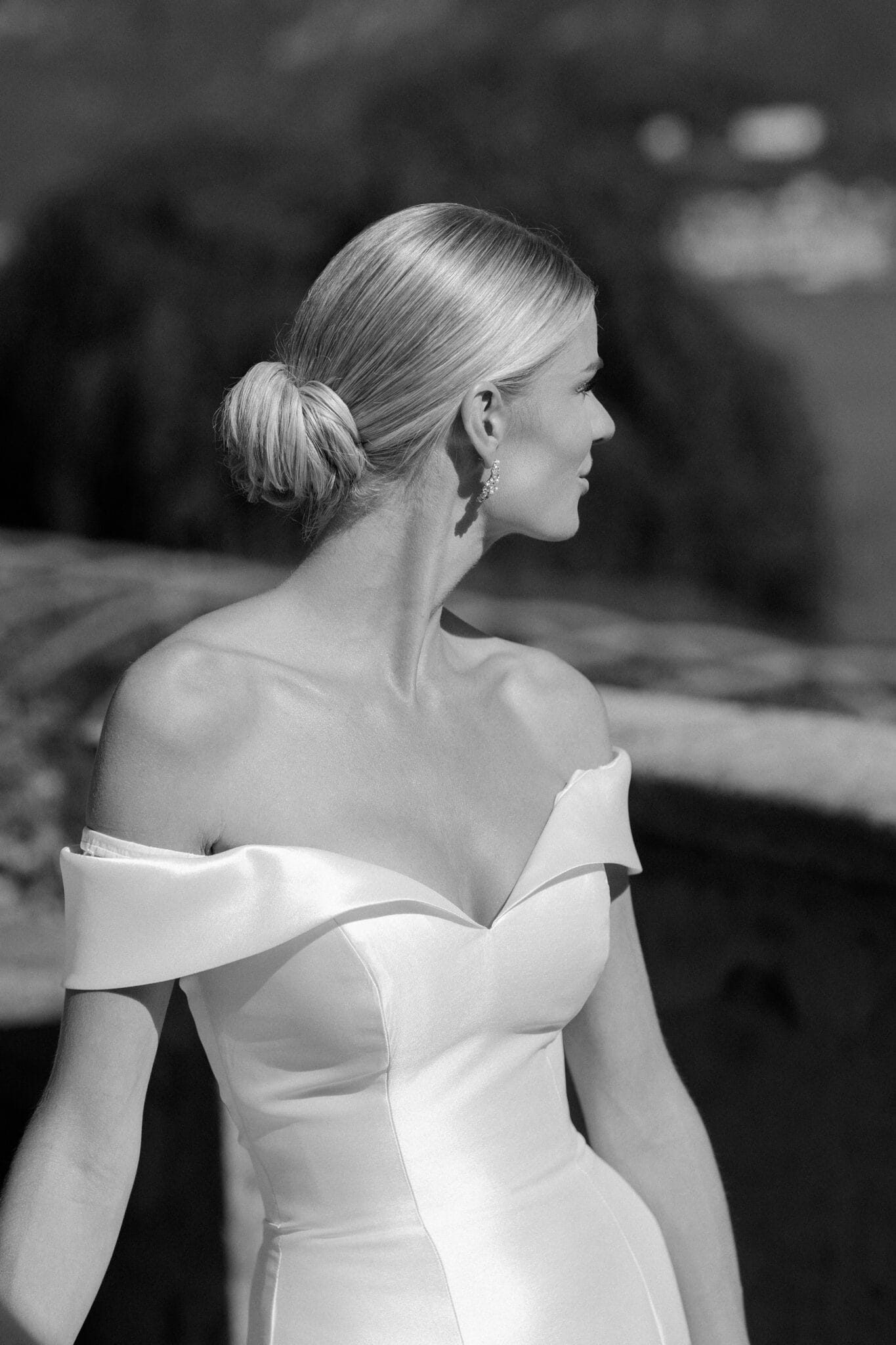Elegant bridal profile in black and white with off-shoulder gown and sleek bun.