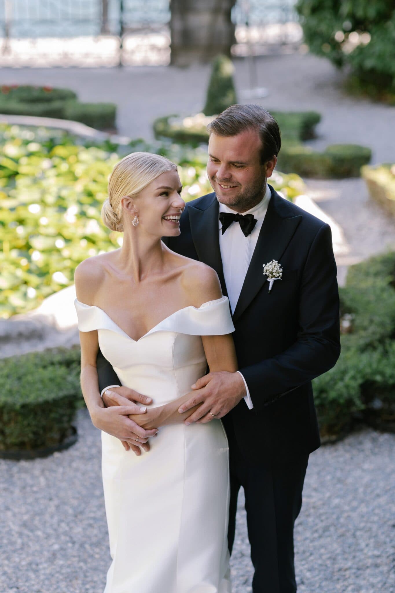 Groom embracing bride as they smile together in Villa Carlotta gardens.