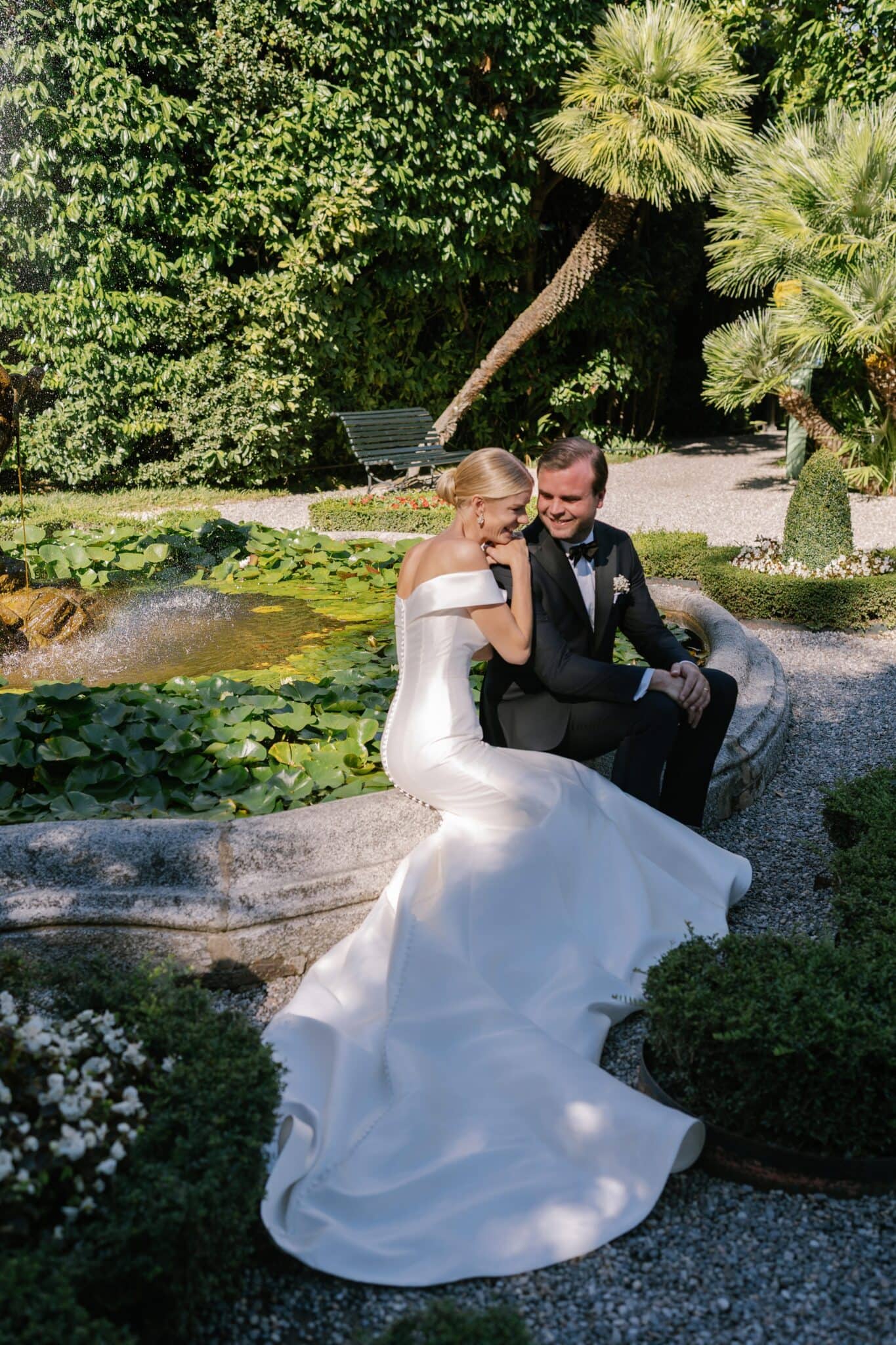 Bride and groom sitting together by the fountain in the gardens of Villa Carlotta.