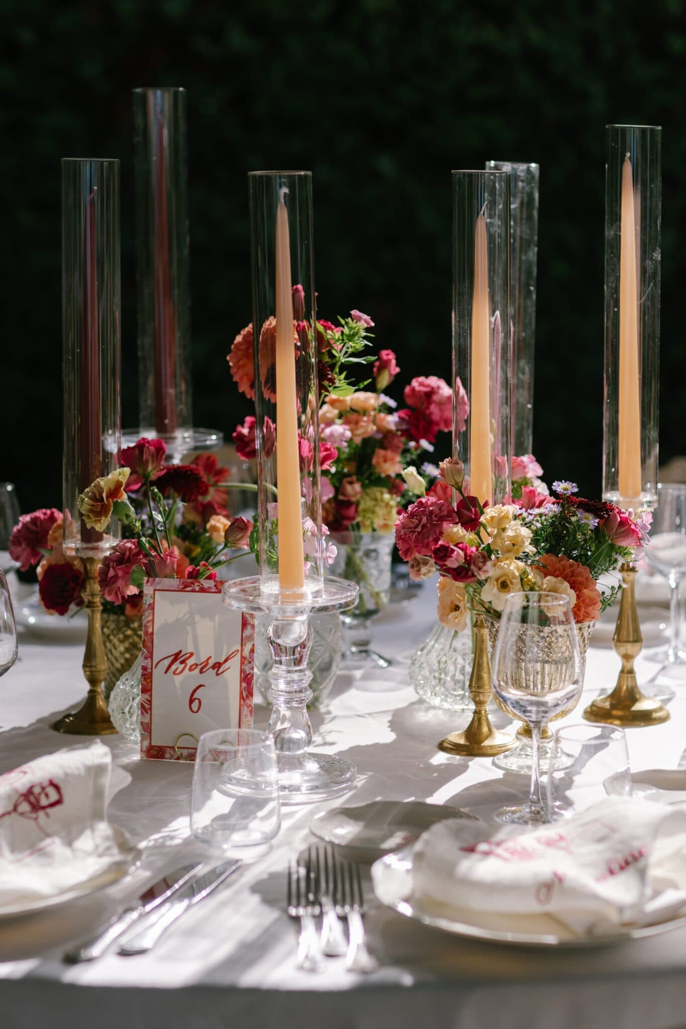 Wedding reception table with tall candles and colorful floral arrangements at Villa Carlotta.