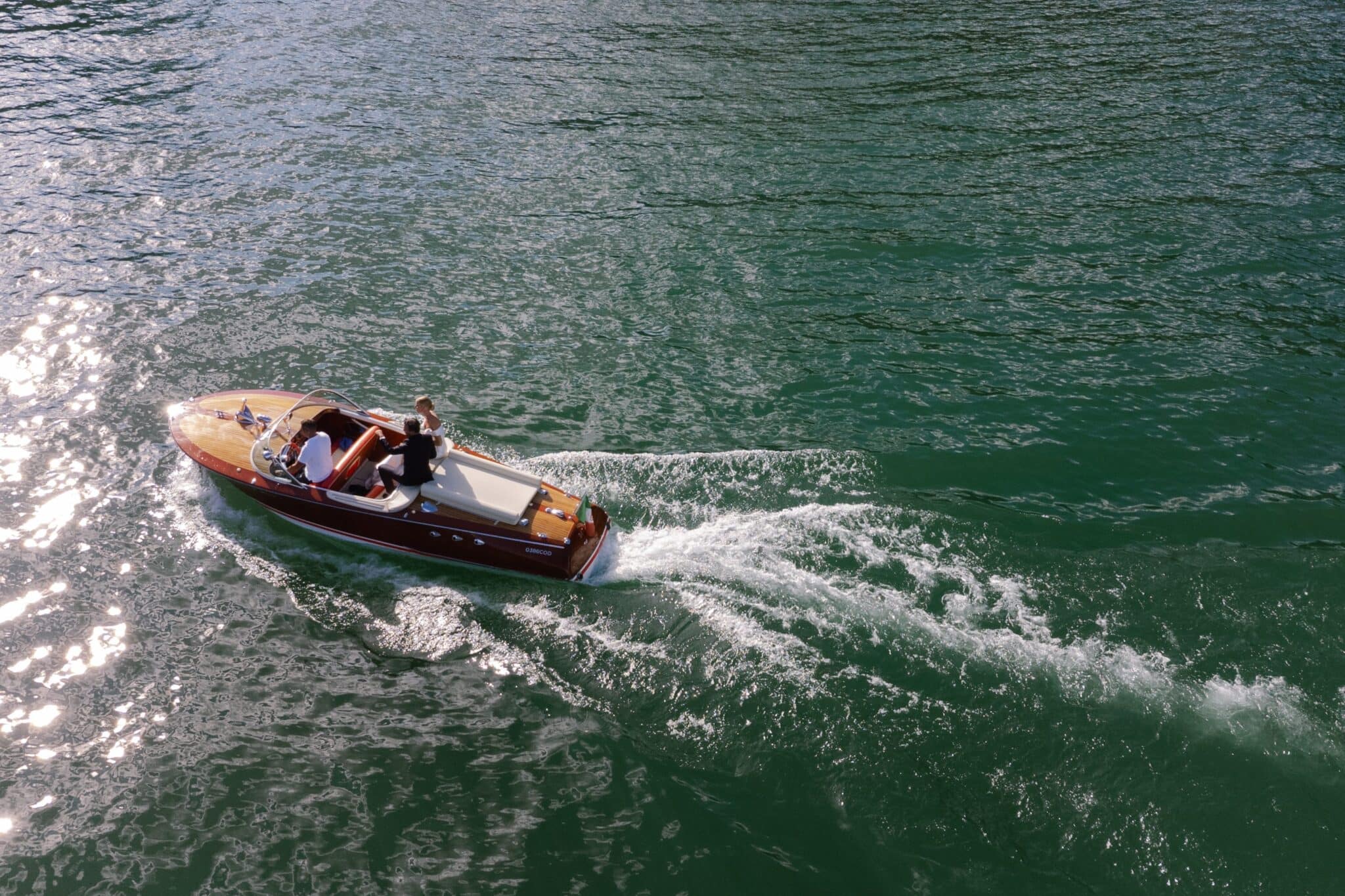 Bride and groom riding a classic wooden speedboat across Lake Como after their wedding.