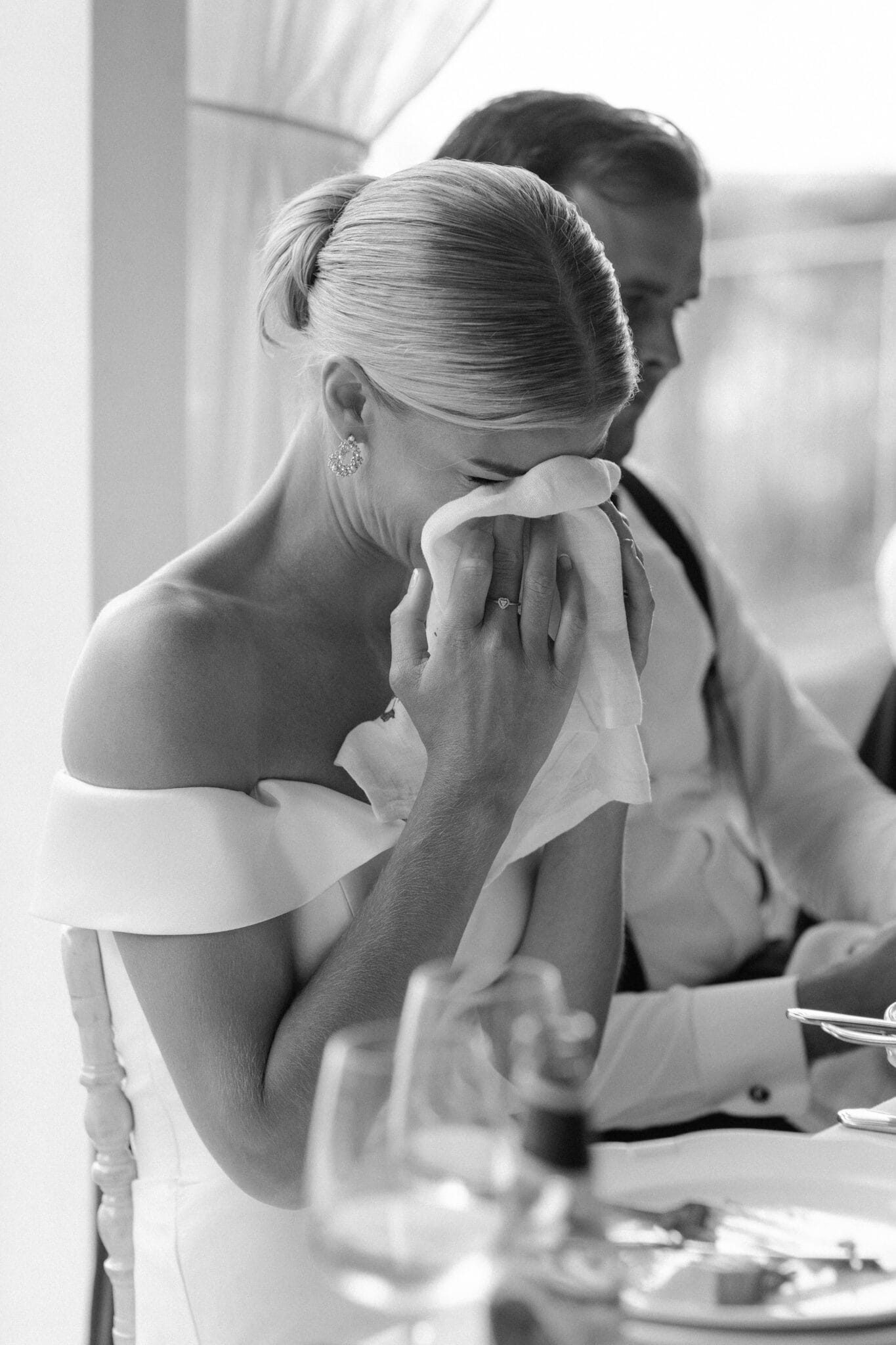 Bride wiping tears of joy during wedding reception speech at Lido di Lenno, black and white.