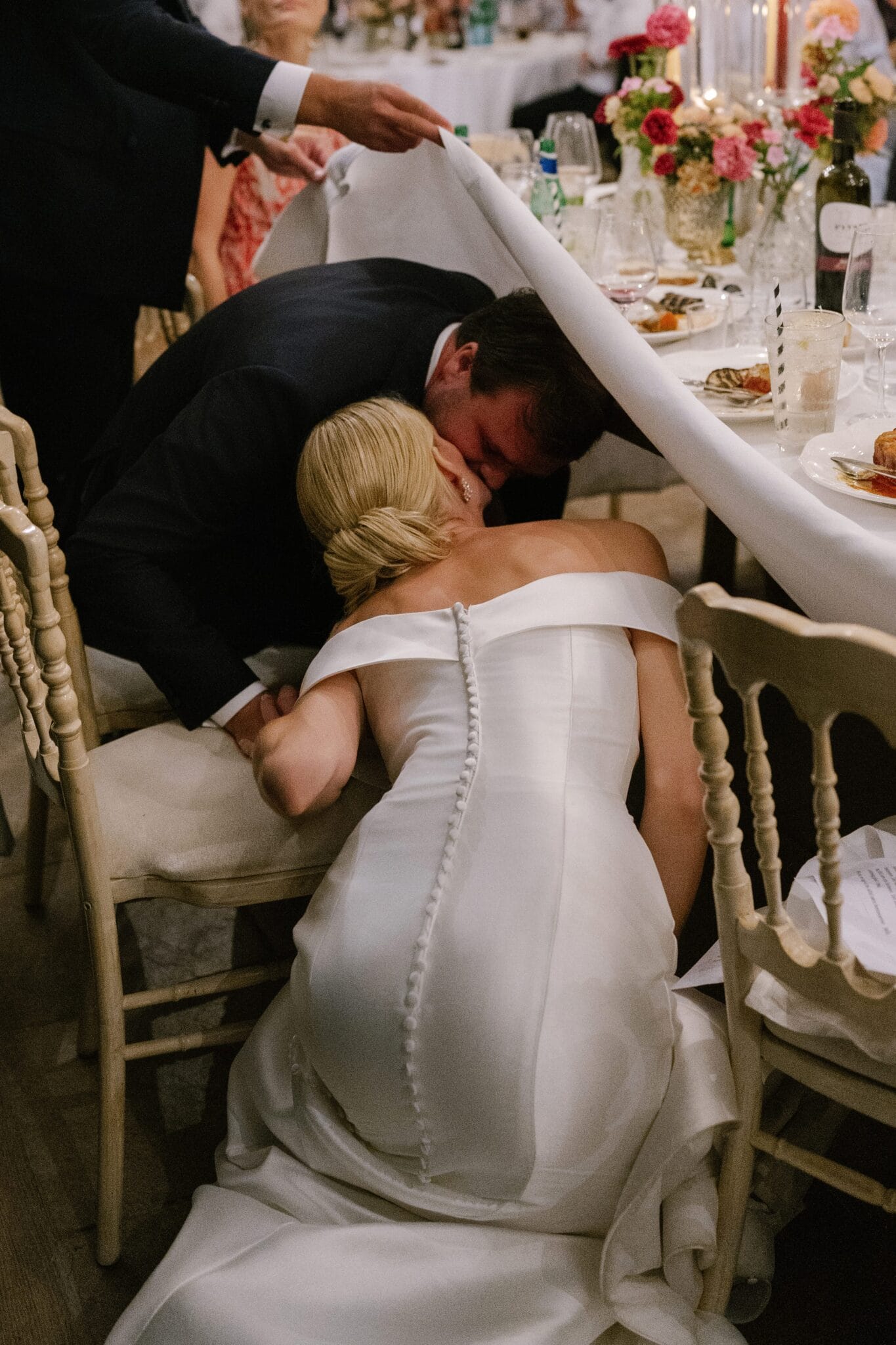 Bride leaning across the table to kiss groom during dinner reception at Villa Carlotta.