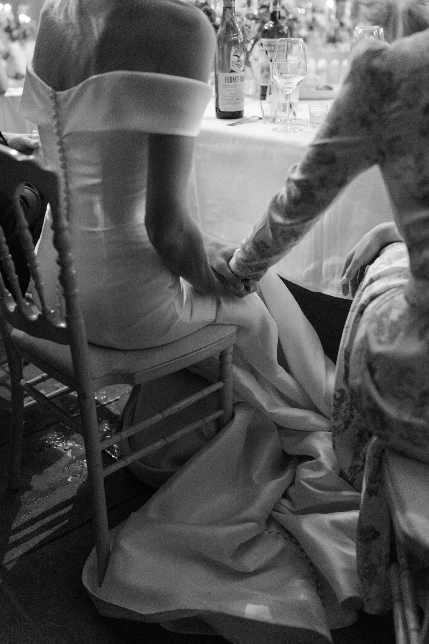 Black-and-white detail of the bride’s gown and a tender hand gesture at the reception in Lido di Lenno.