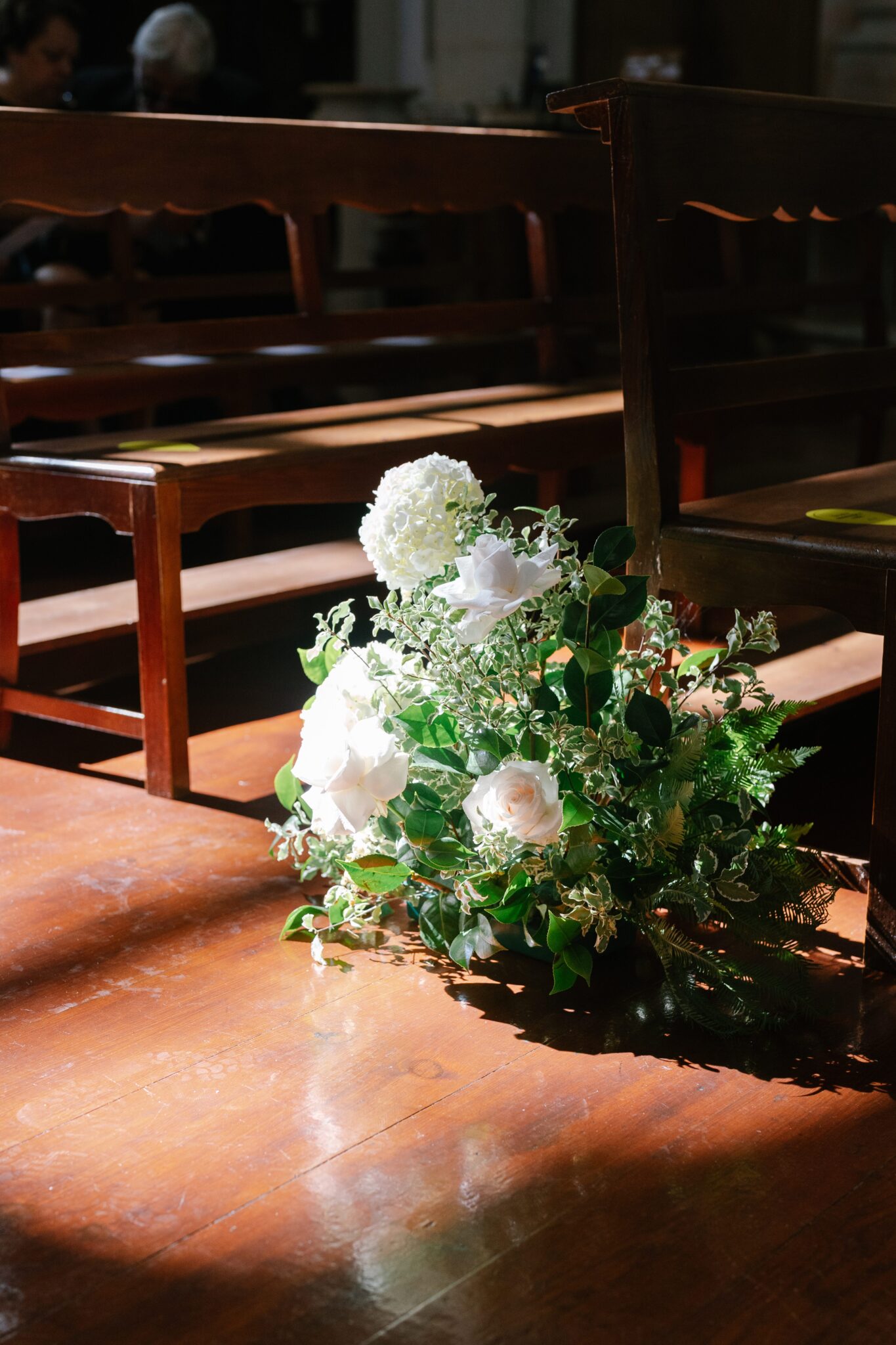 White rose and greenery floral arrangement illuminated by sunlight inside church in Portugal
