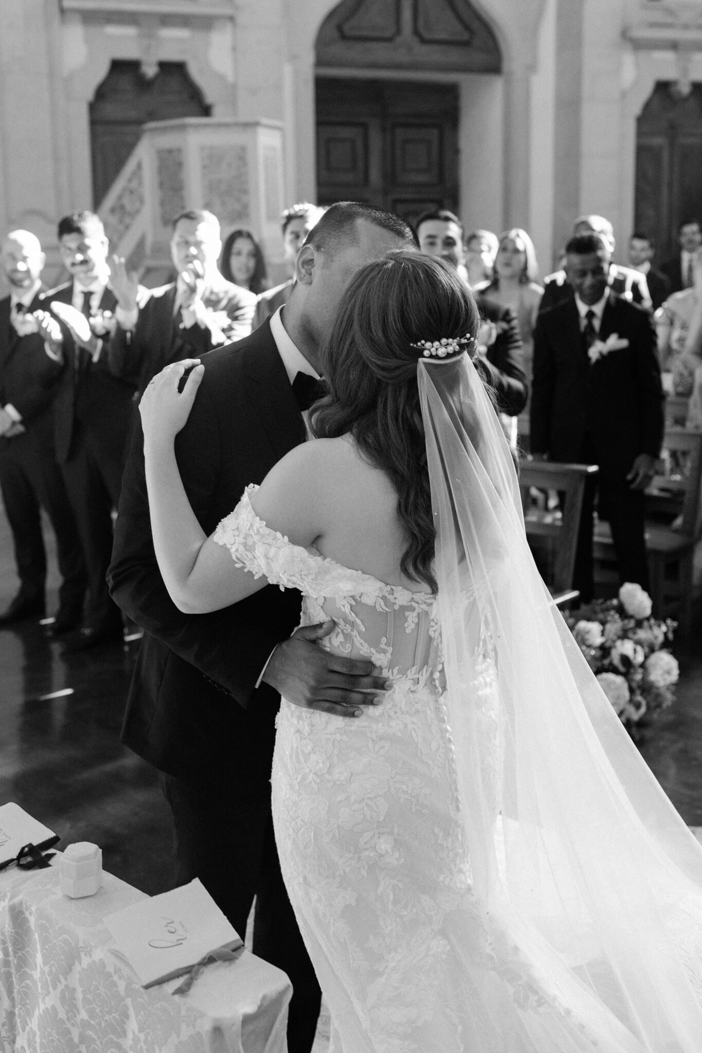 Bride and groom kissing during church ceremony surrounded by guests in Portugal
