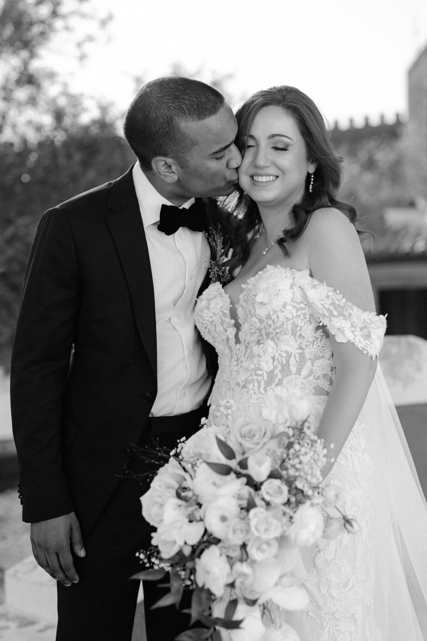 Groom kissing bride on the cheek in black and white wedding portrait Portugal