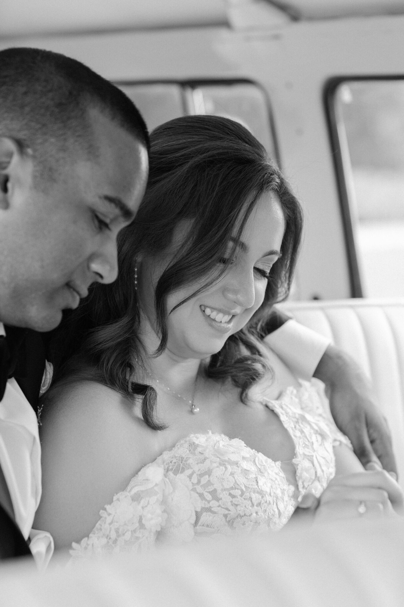 Bride and groom sitting inside vintage van sharing tender moment black and white photo