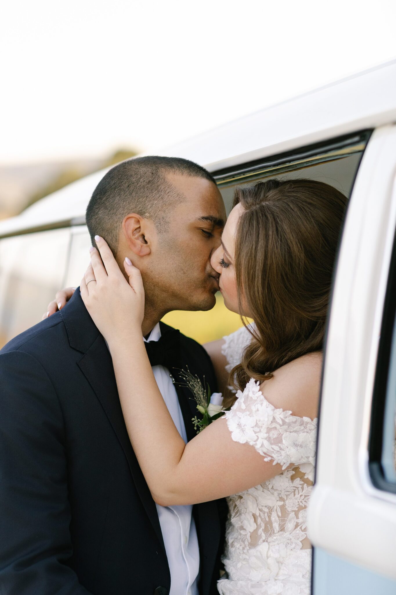 Bride and groom sharing a kiss by vintage VW van at vineyard wedding in Portugal