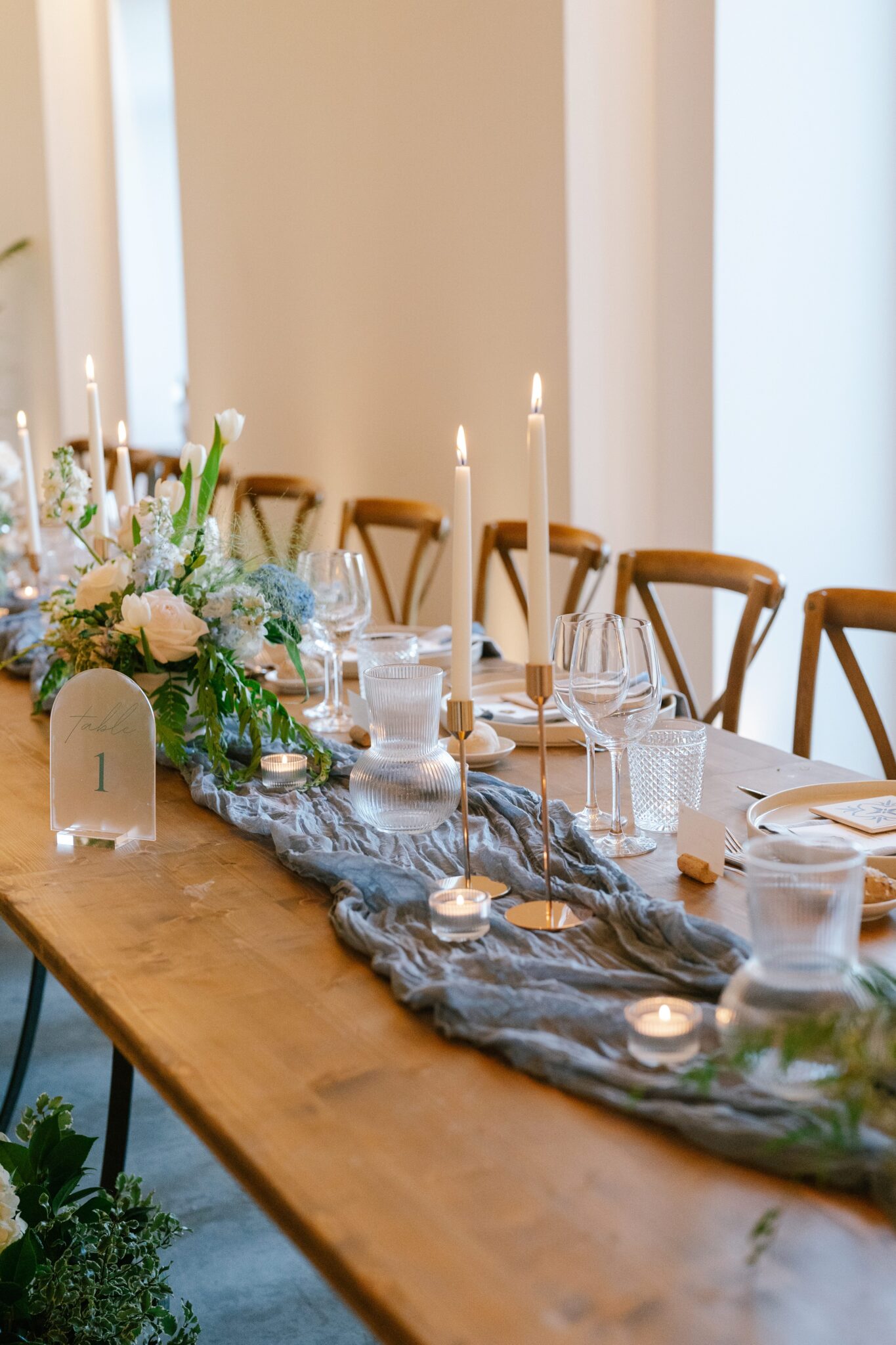 Elegant wooden wedding table decorated with candles, greenery, and white florals at Quinta do Gradil in Portugal