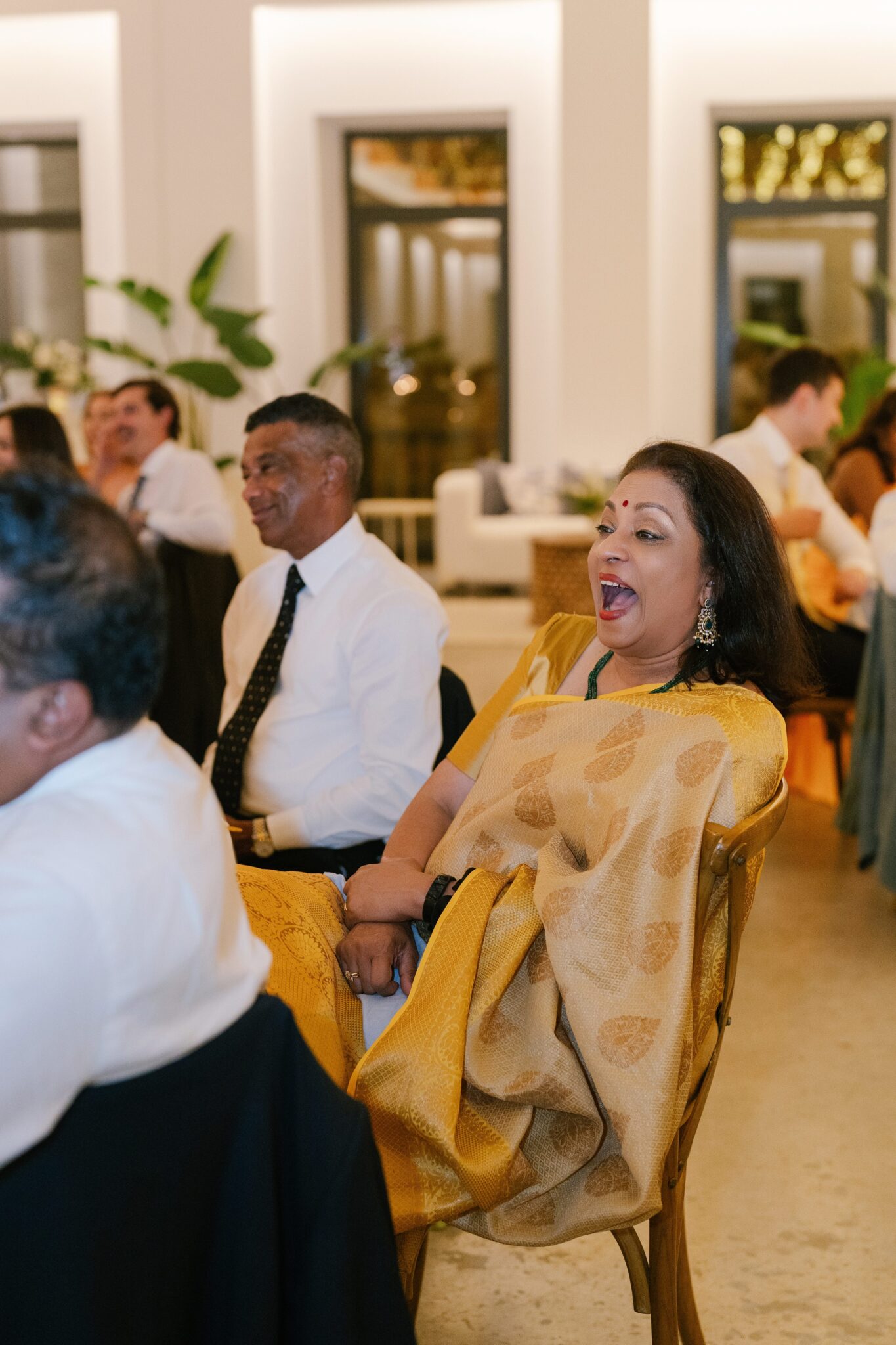 Wedding guest in golden sari laughing during evening reception in Portugal